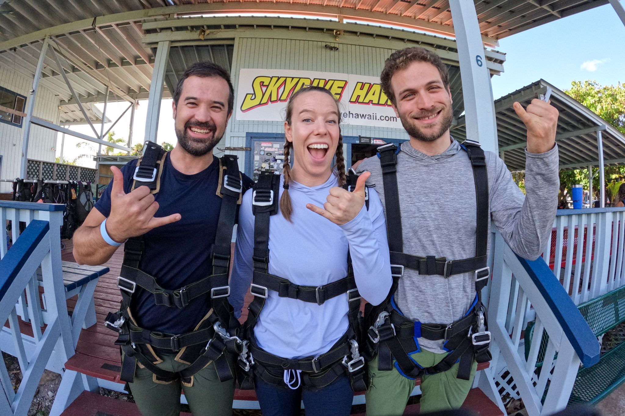 Three people posing in front of a skydiving business in Hawaii. 