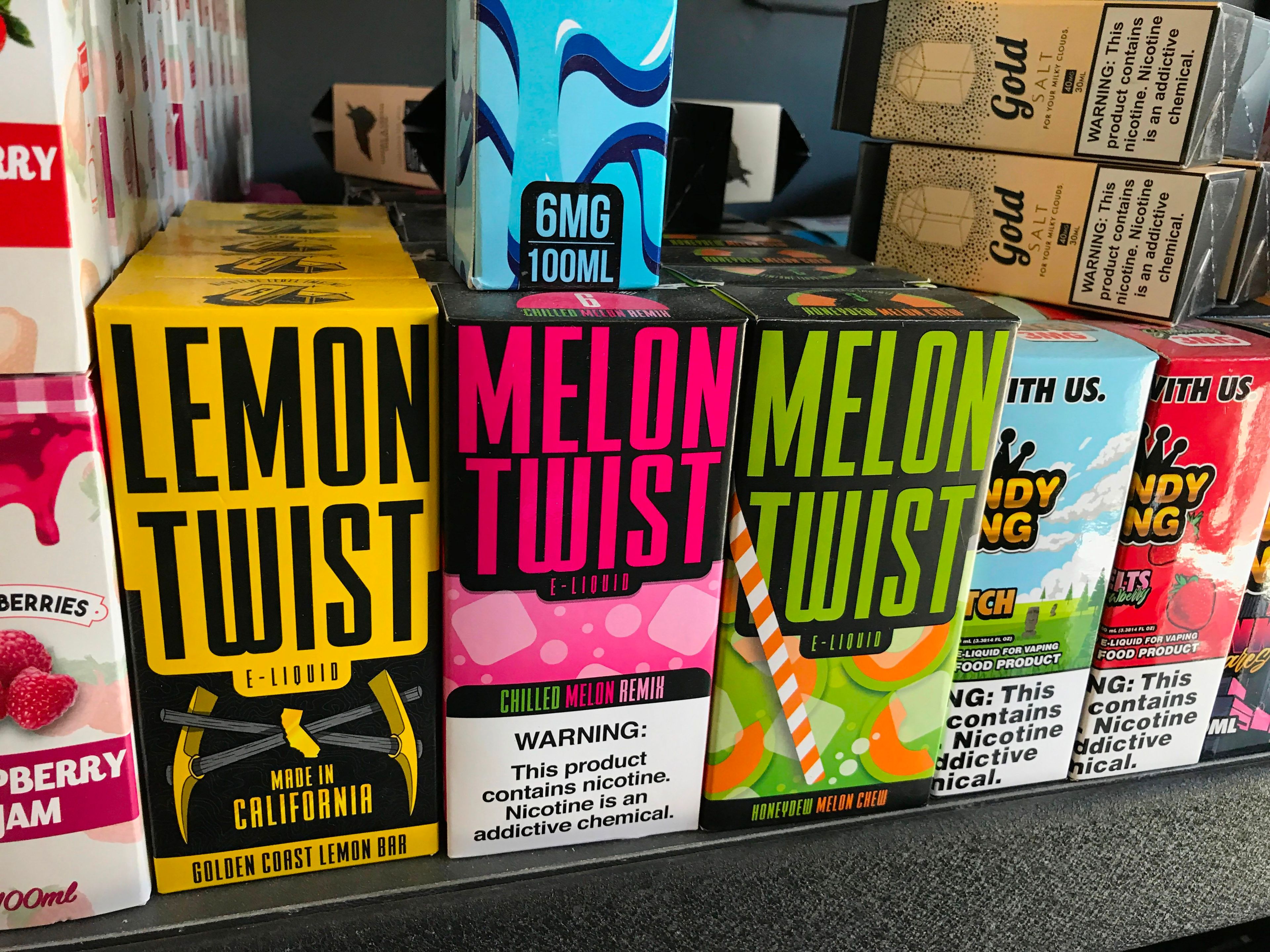 A collection of vape products in various flavors, including lemon twist and lemon twist, on a store shelf.