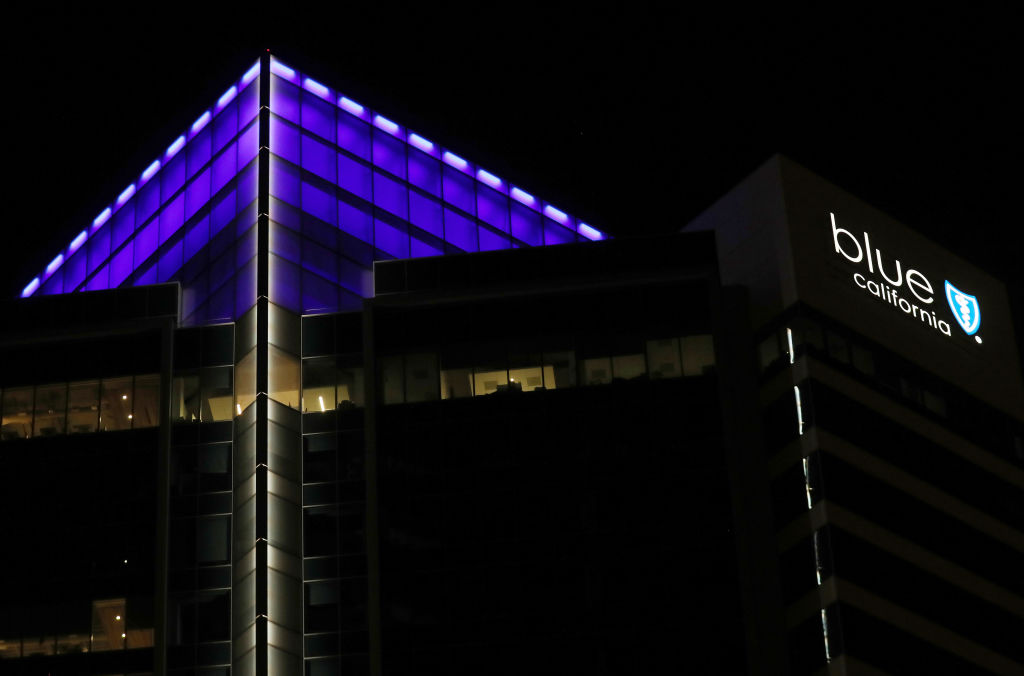 A tall office building is lit with blue lights.