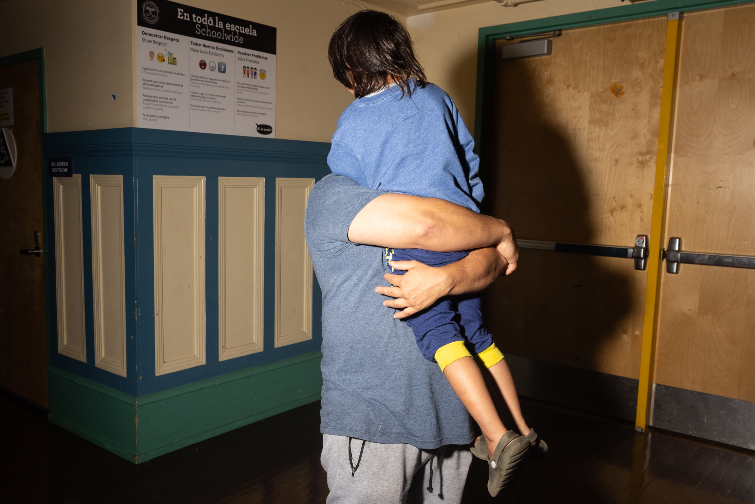 A man holds a child in a firm hug.
