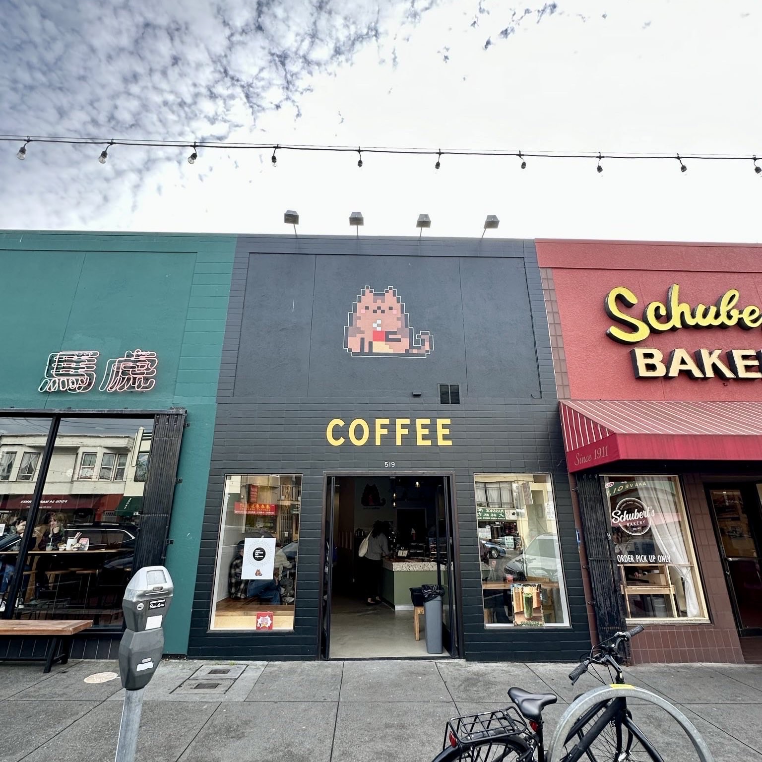 A photo shows a black storefront that says &quot;coffee&quot; on it with a pixellated cat above it. 