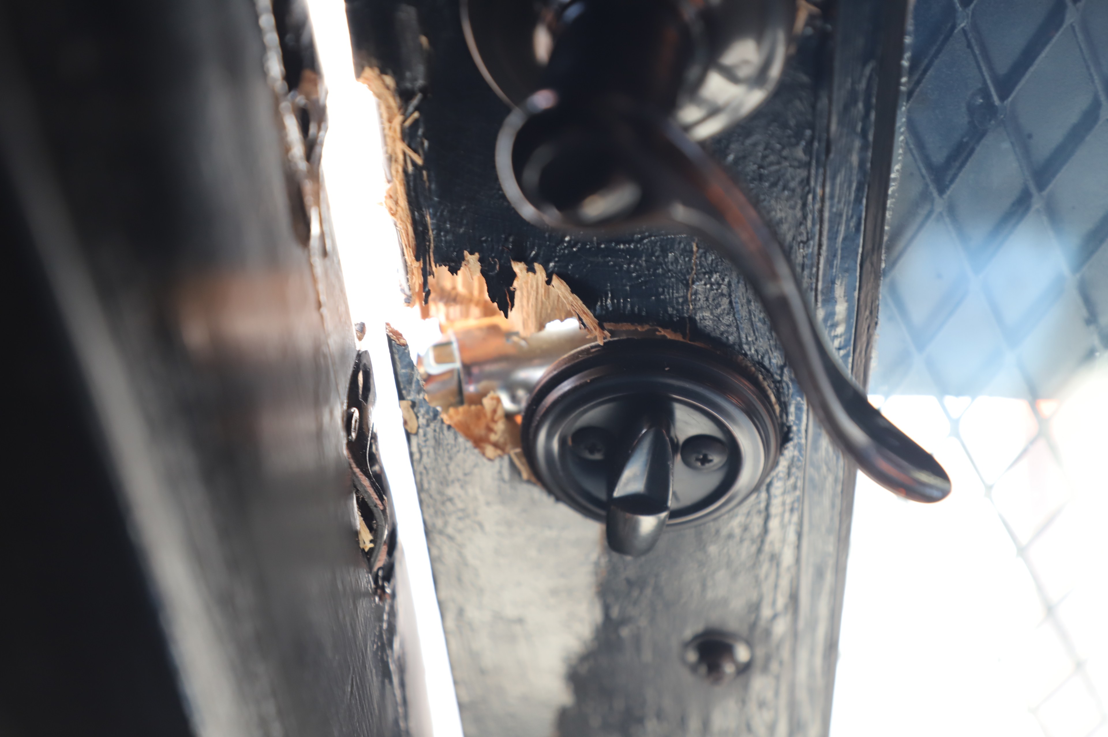 A door lock sits broken inside of a door frame.