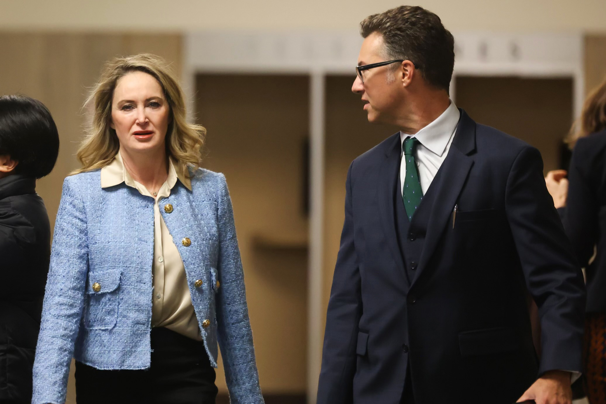 A woman, Yvette Corkrean, left, and a man, her attorney walk through the hallways of the Hall of Justice at Superior Court with people in the the background.