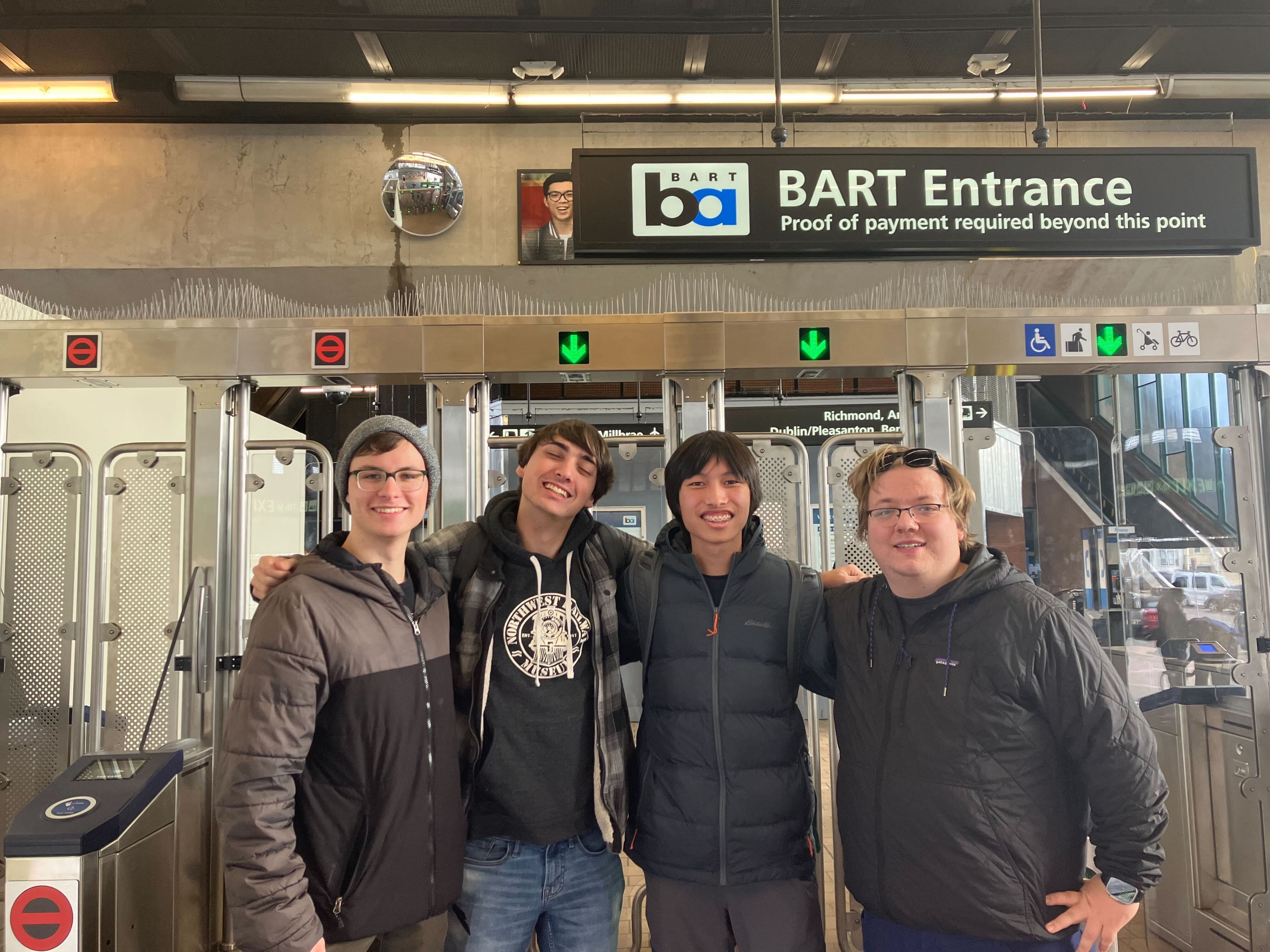 Clark Merrick (far left) stands alongside his friends Sam Jeffs, Lukas Chiu and Sergio Zygmunt in front of the newly opened fare gates at West Oakland Station on Dec. 28, 2023.