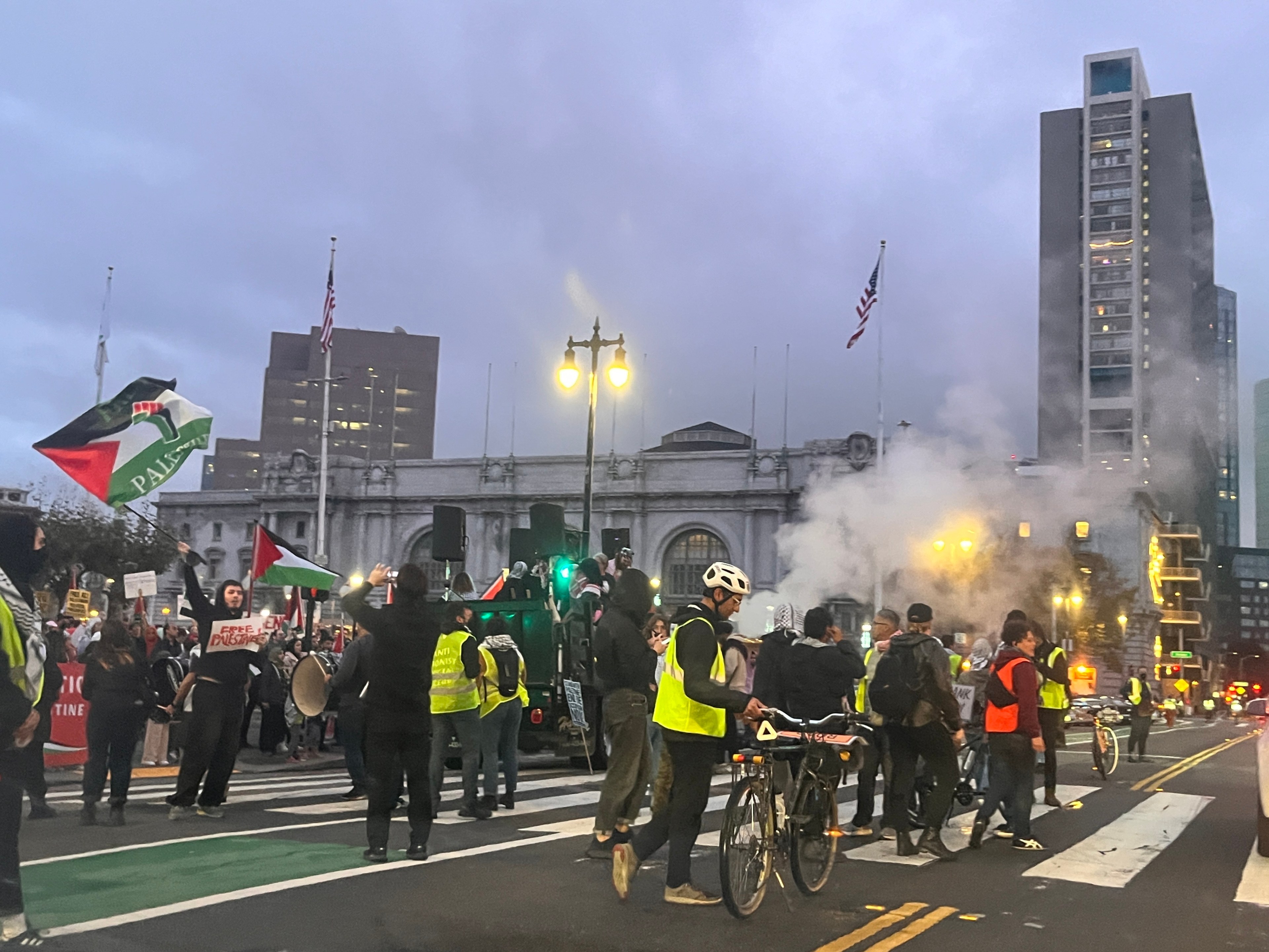 Protesters wave Palestinian flags under a foggy sky outside San Francisco City Hall.