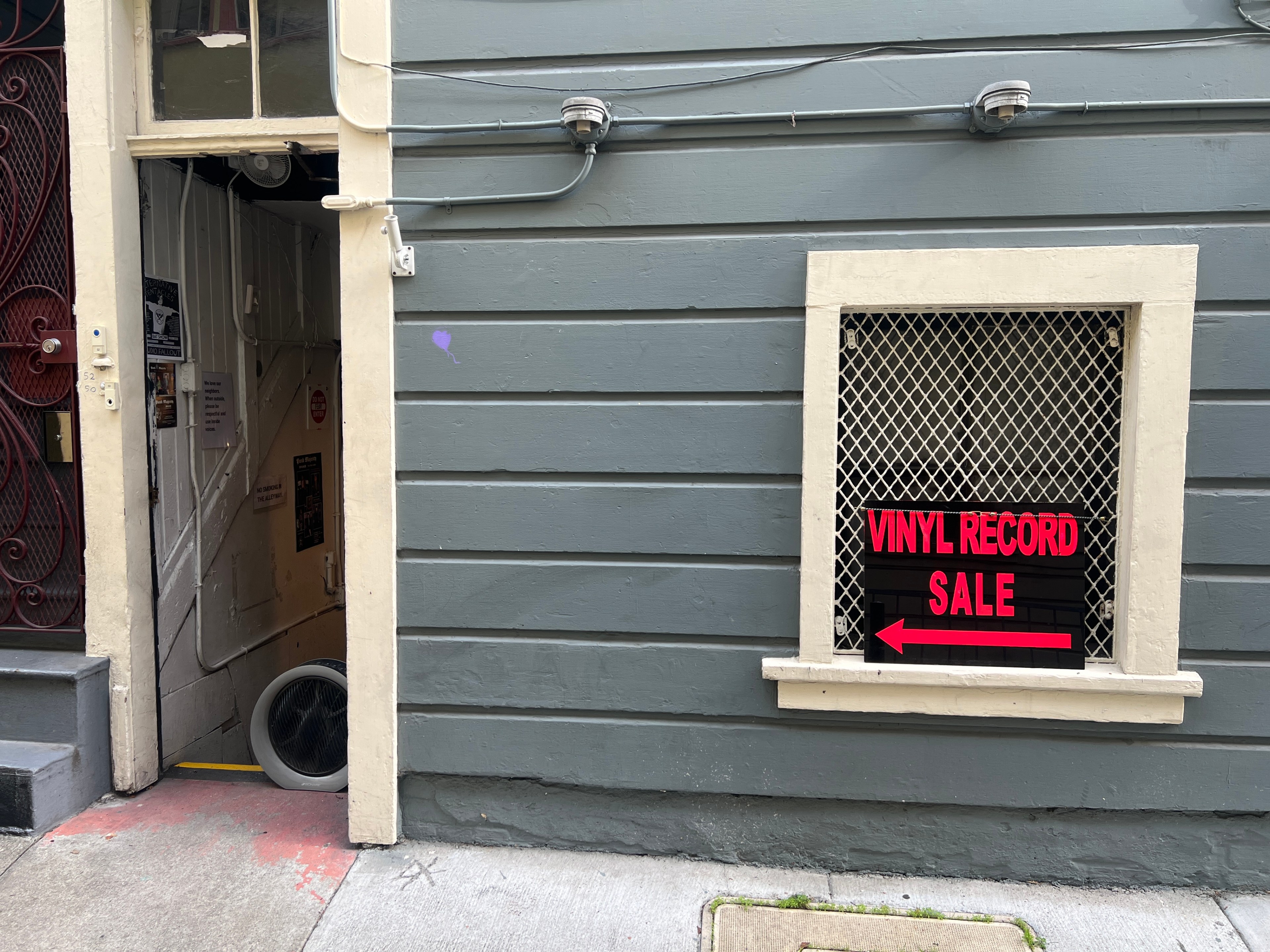 A gray wall has a window with a sign that says &quot;Vinyl Record Sale.&quot;