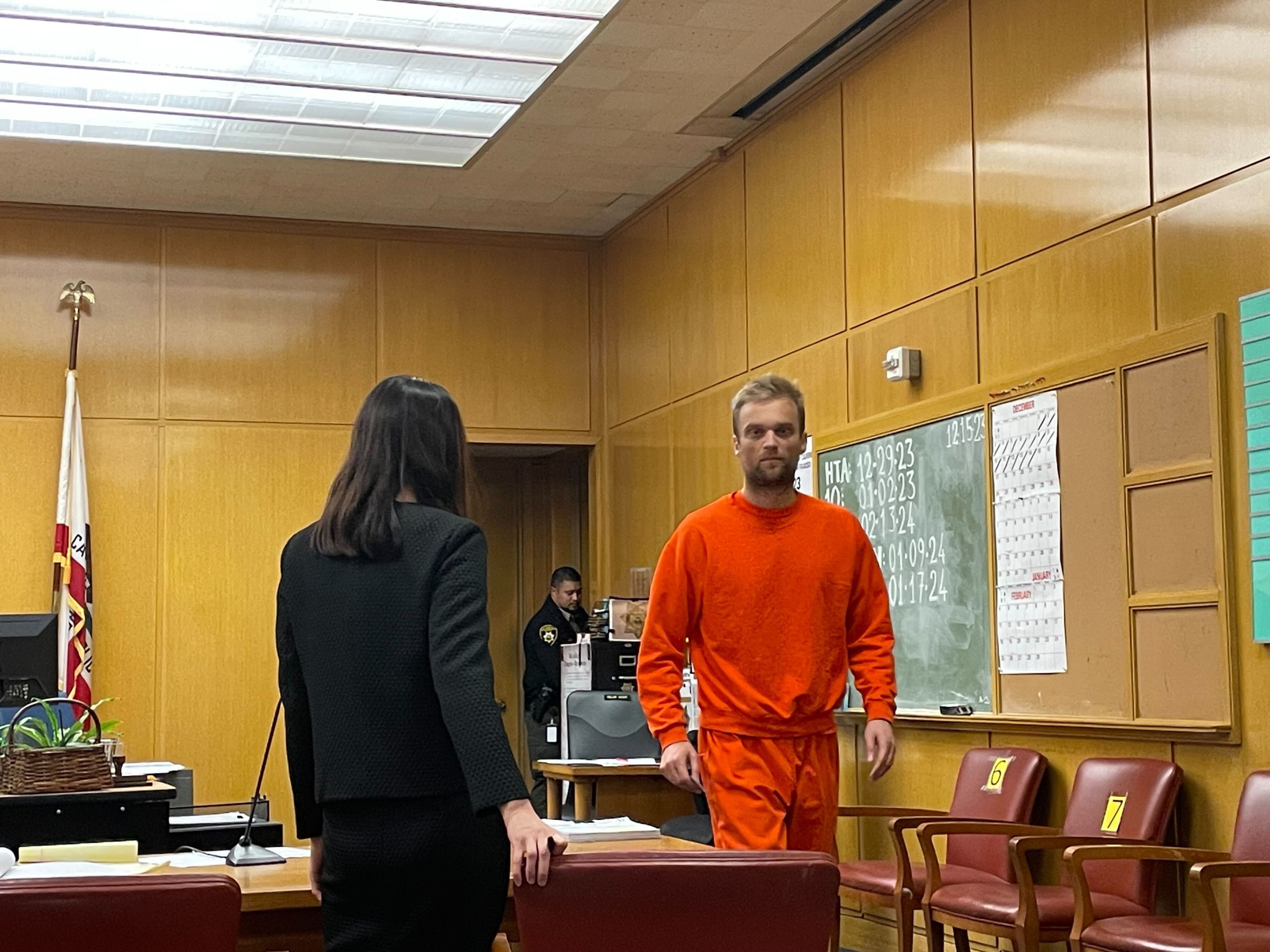 a man in an orange jumpsuit walks through a court room