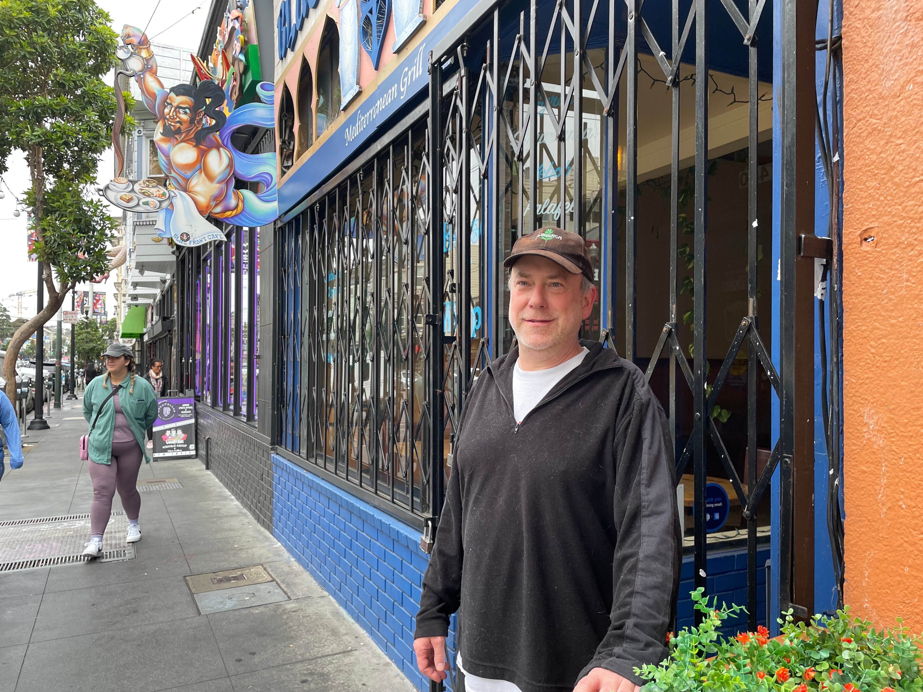 A man stands in front of a restaurant.