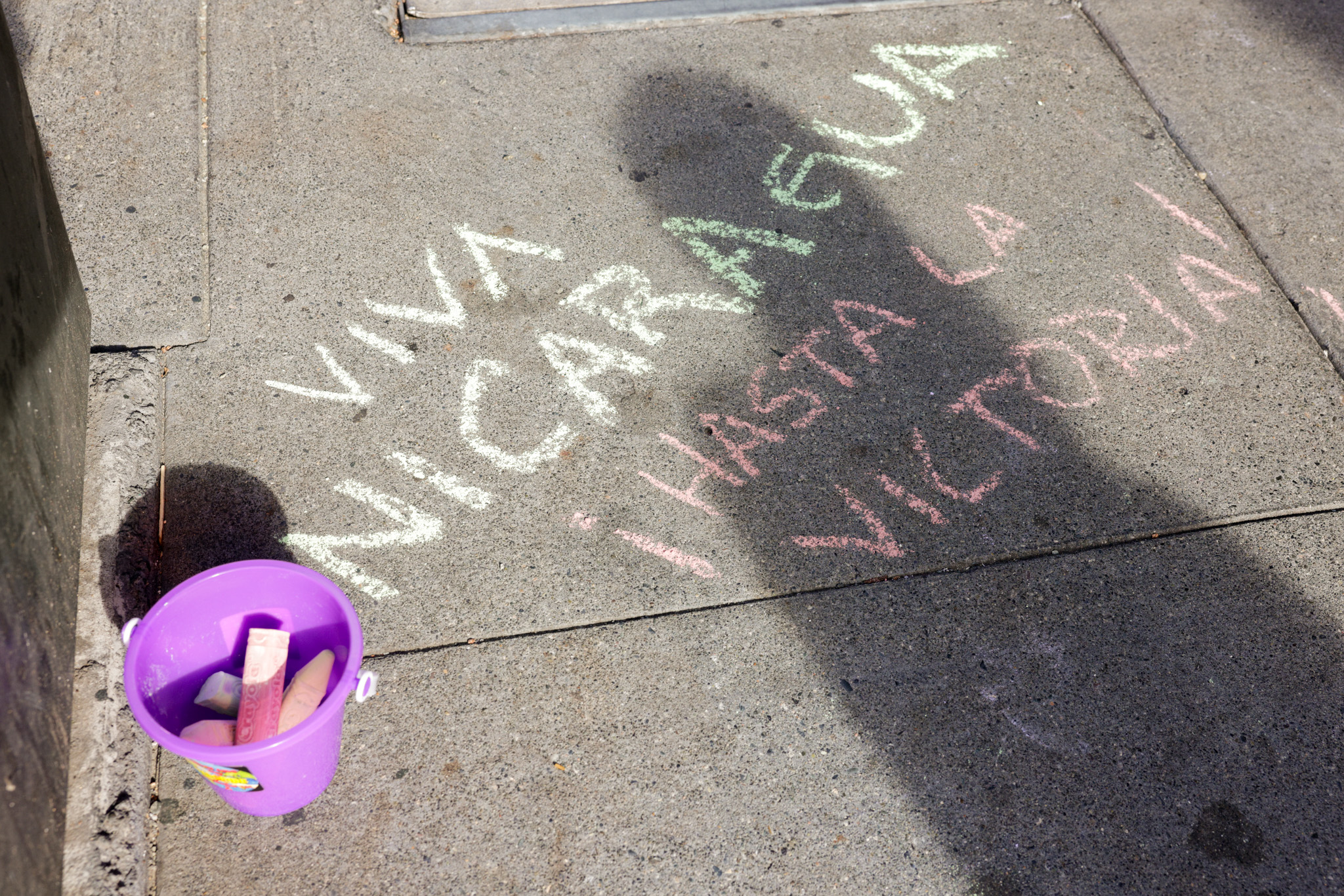 A purple plastic cup with chalk with a person shadow over someones name.