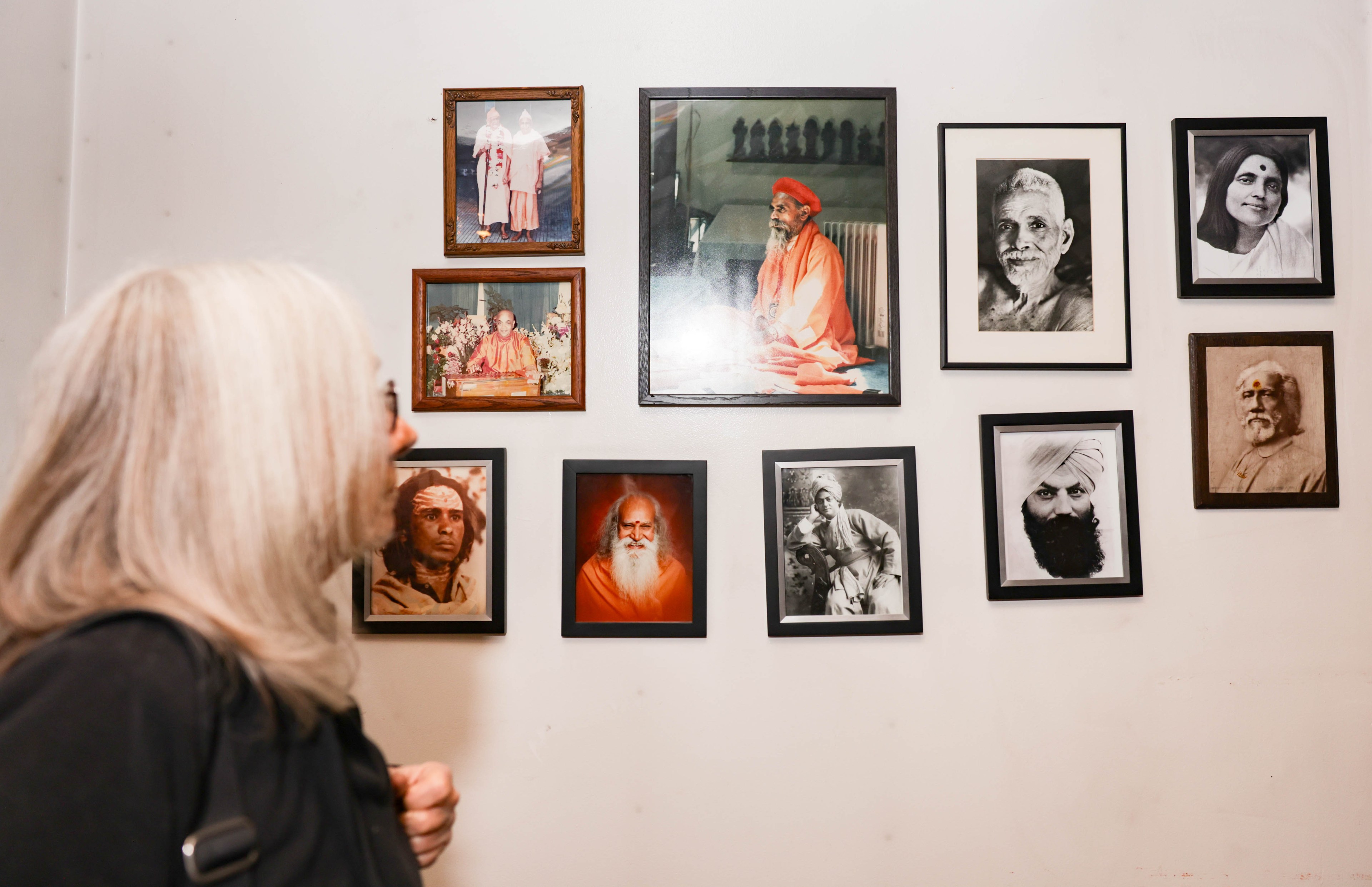 A person walks by a wall of yogis and spiritual advisors.