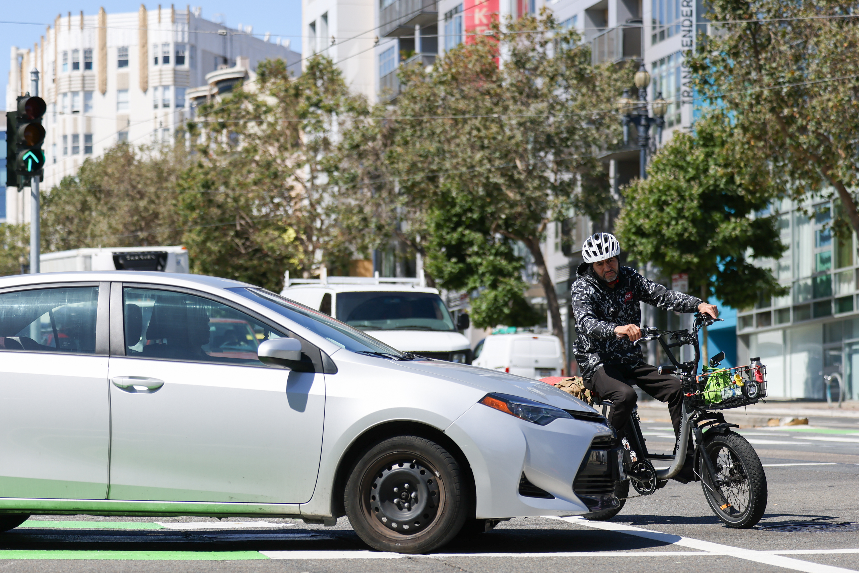 A cyclist maneuvers around gridlocked cars at the intersection.