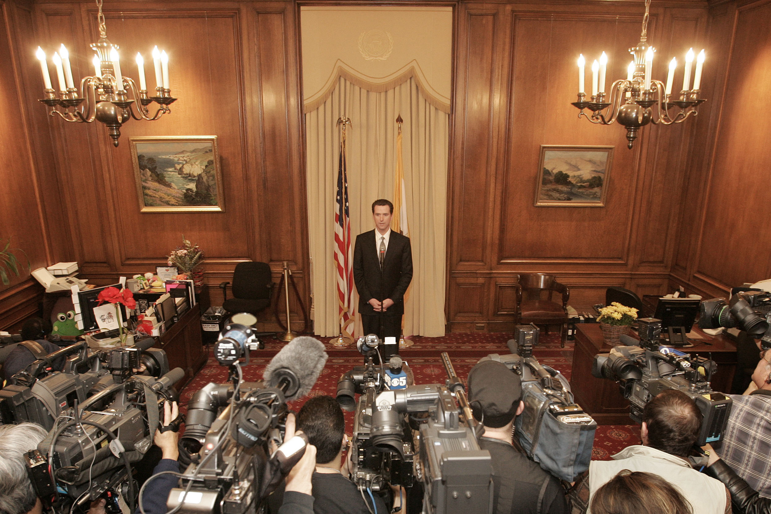 San Francisco Mayor Gavin Newsom holds a morning press conference as member of media look on.