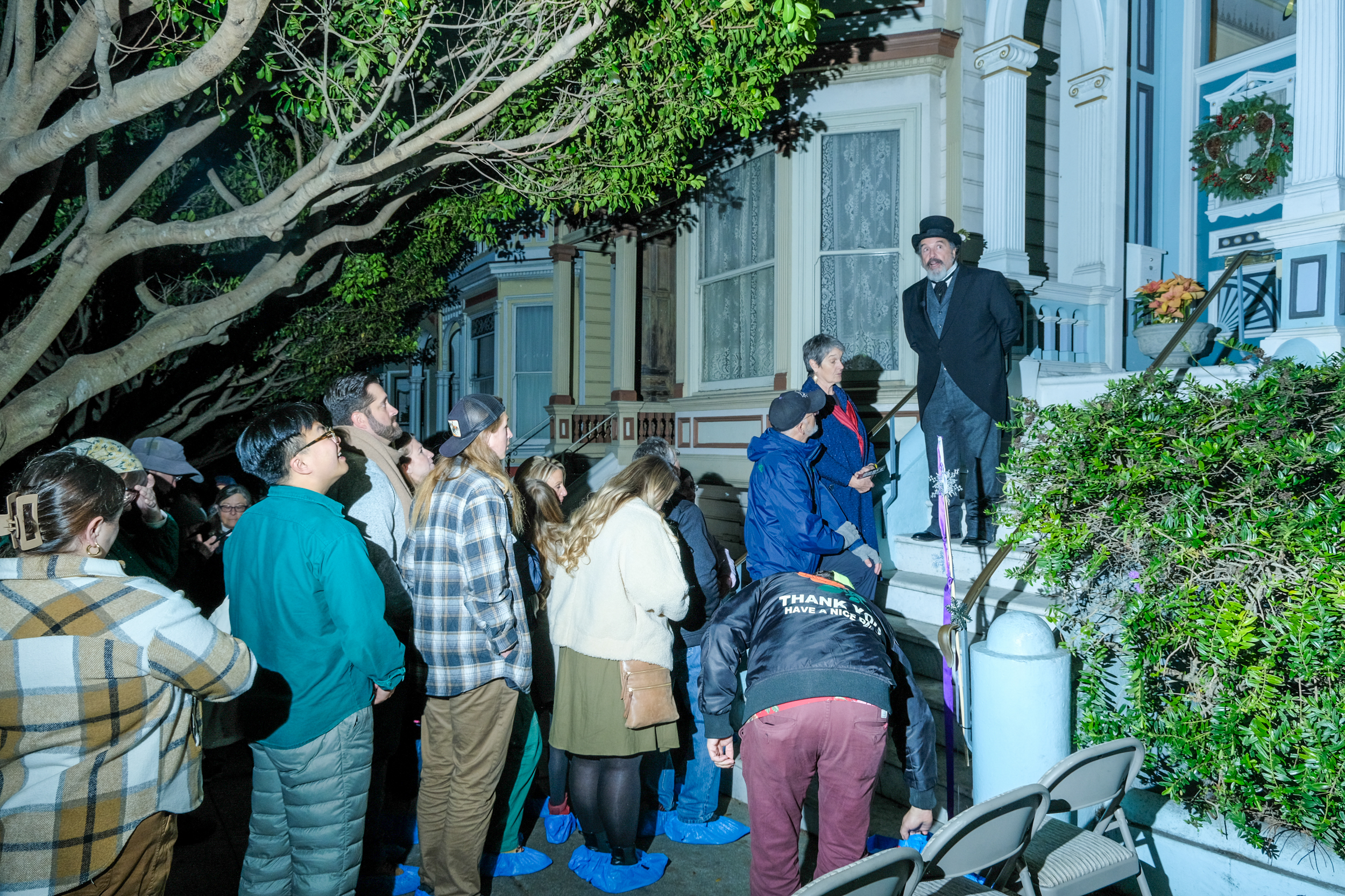 A line of people wait to get in an old victorian house.