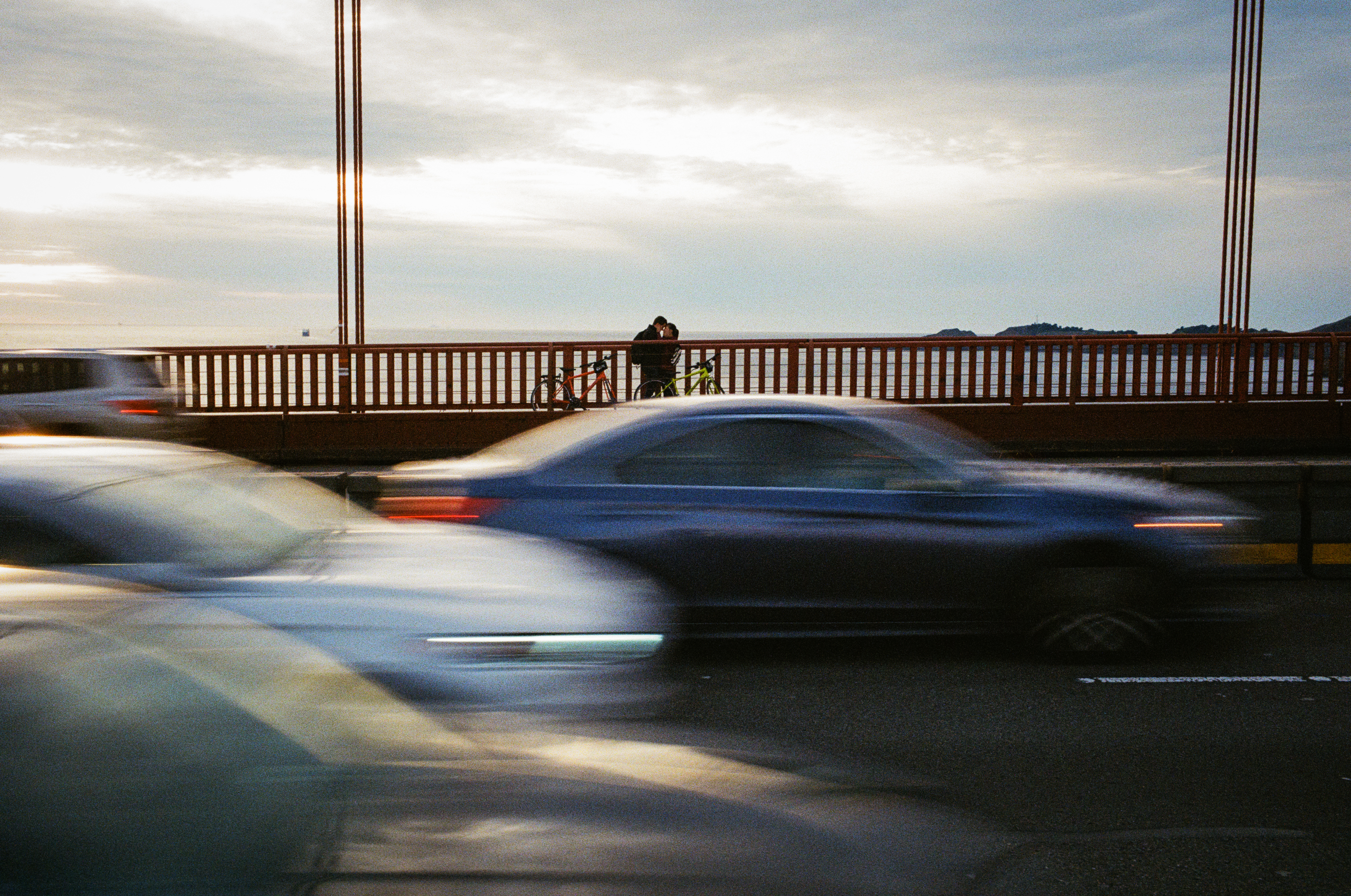 Two people across the hug on the Golden Gate Bridge as cars pass by in November 2020.