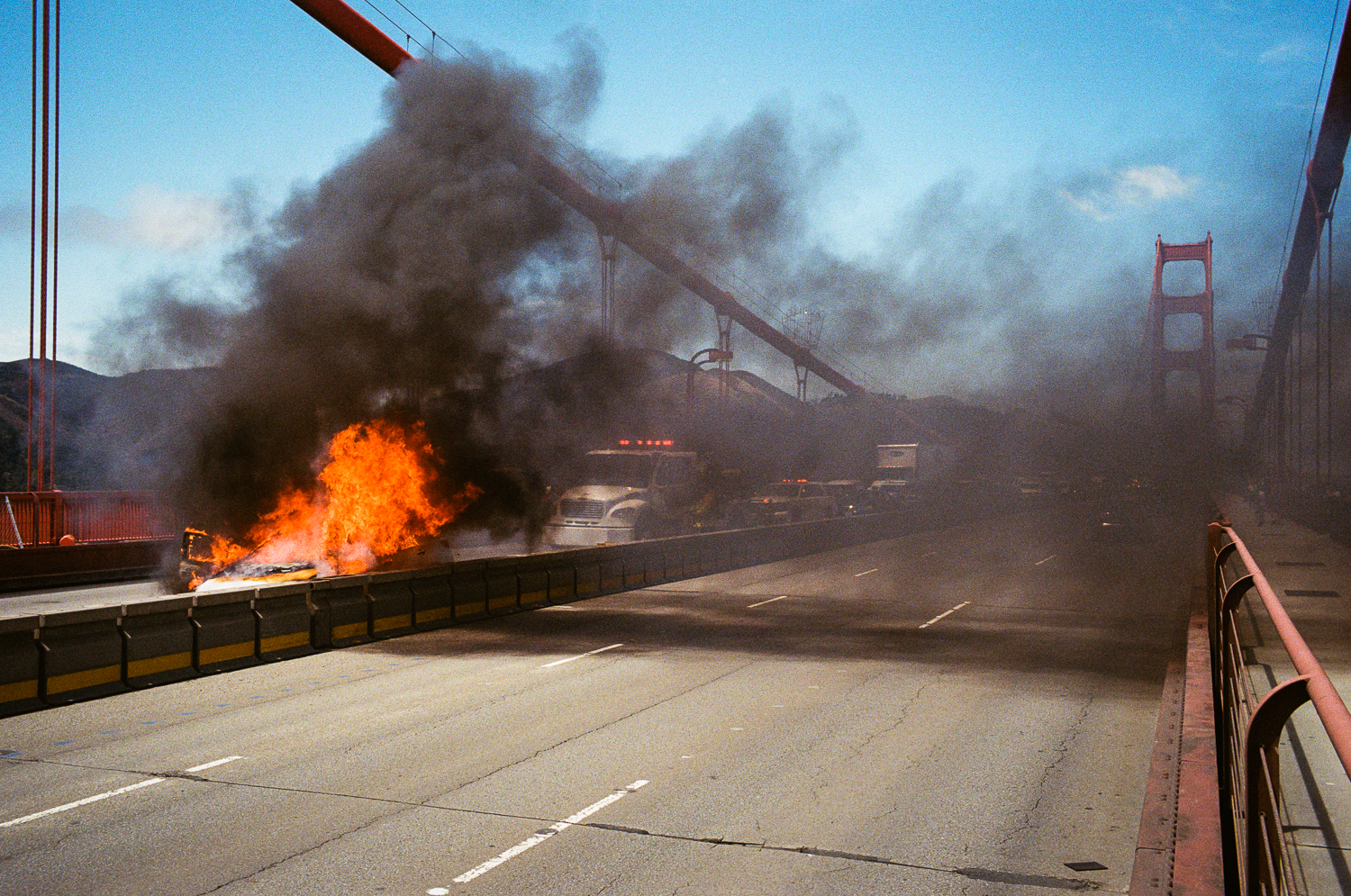 Emergency vehicles respond to a car on fire near the middle of the bridge in July 2020.