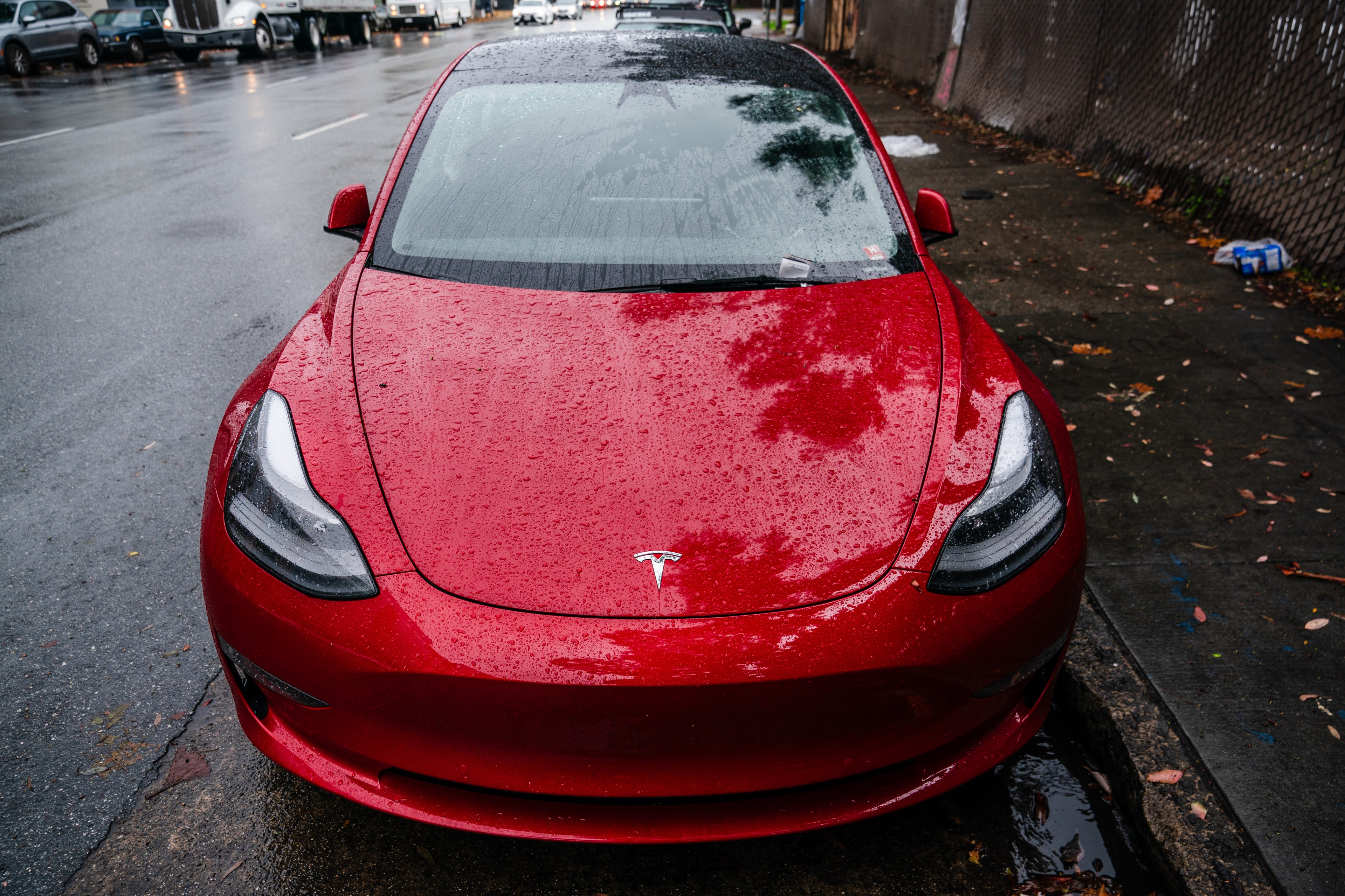 A red Tesla Model 3 with no front license plate.