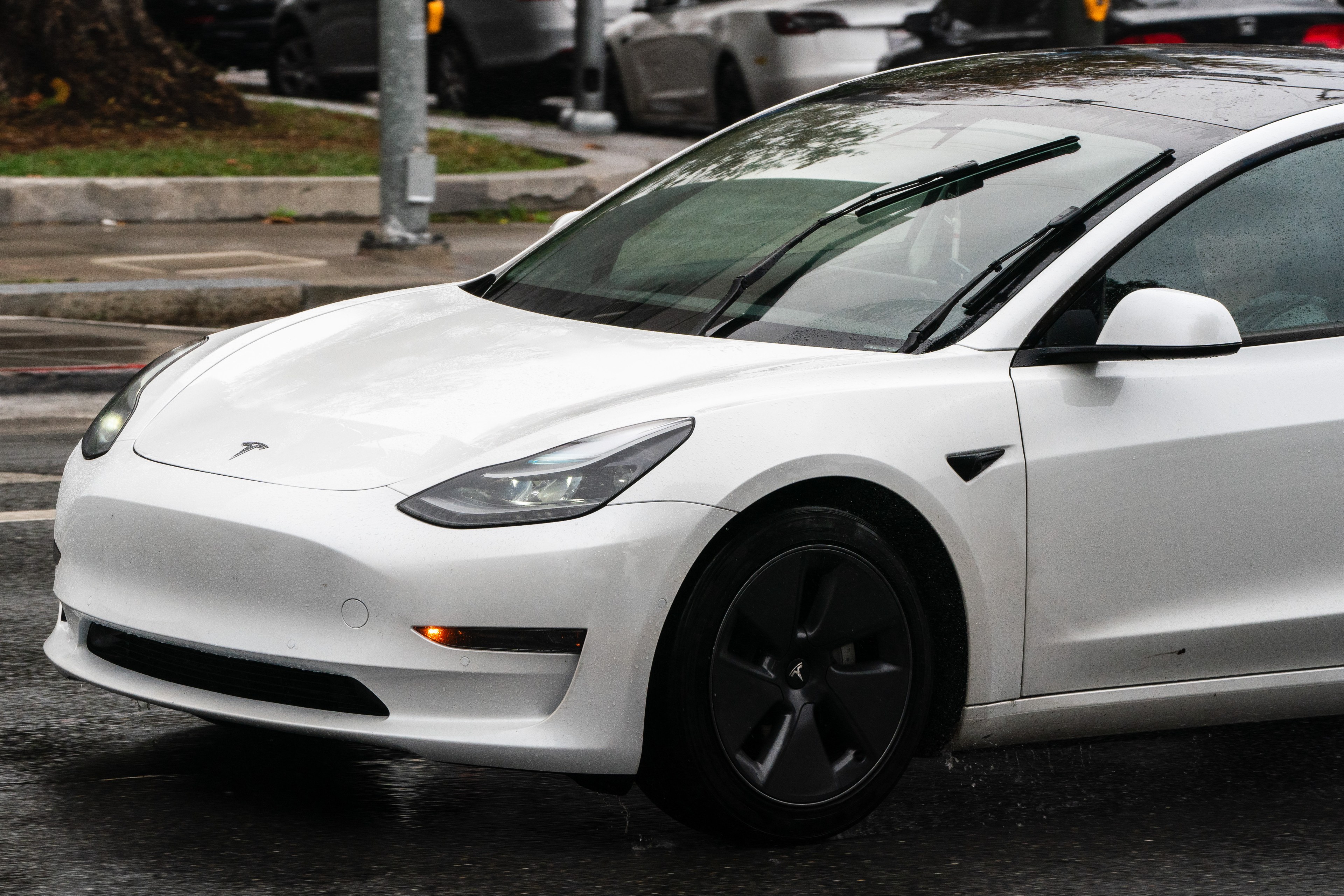 A white Tesla Model 3 with no front license plate.