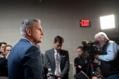 Kevin McCarthy stands before the press with an exit sign in the distance