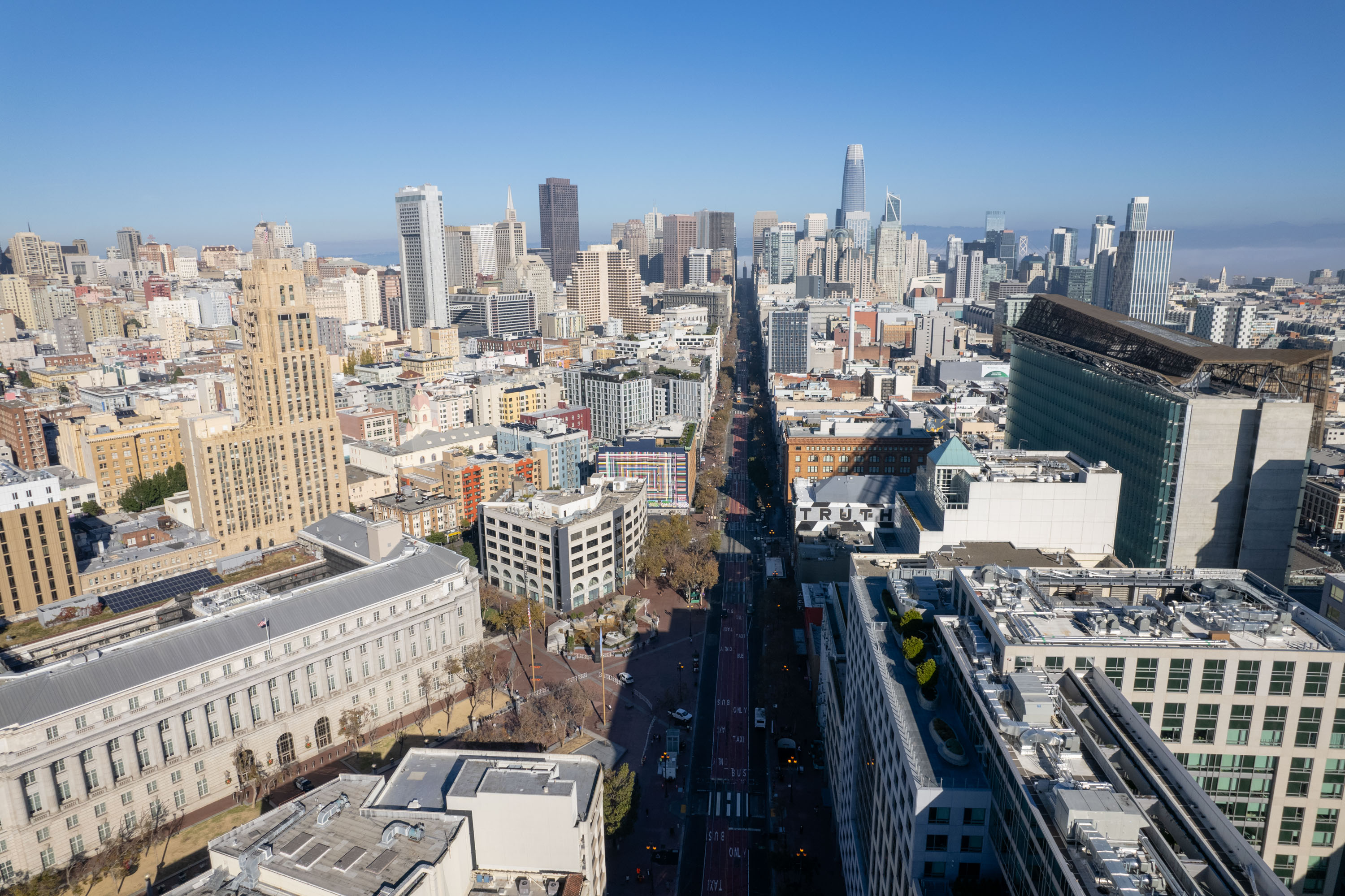 An aerial view of Market street with buildings on both sides and the San Francisco City Skyline.