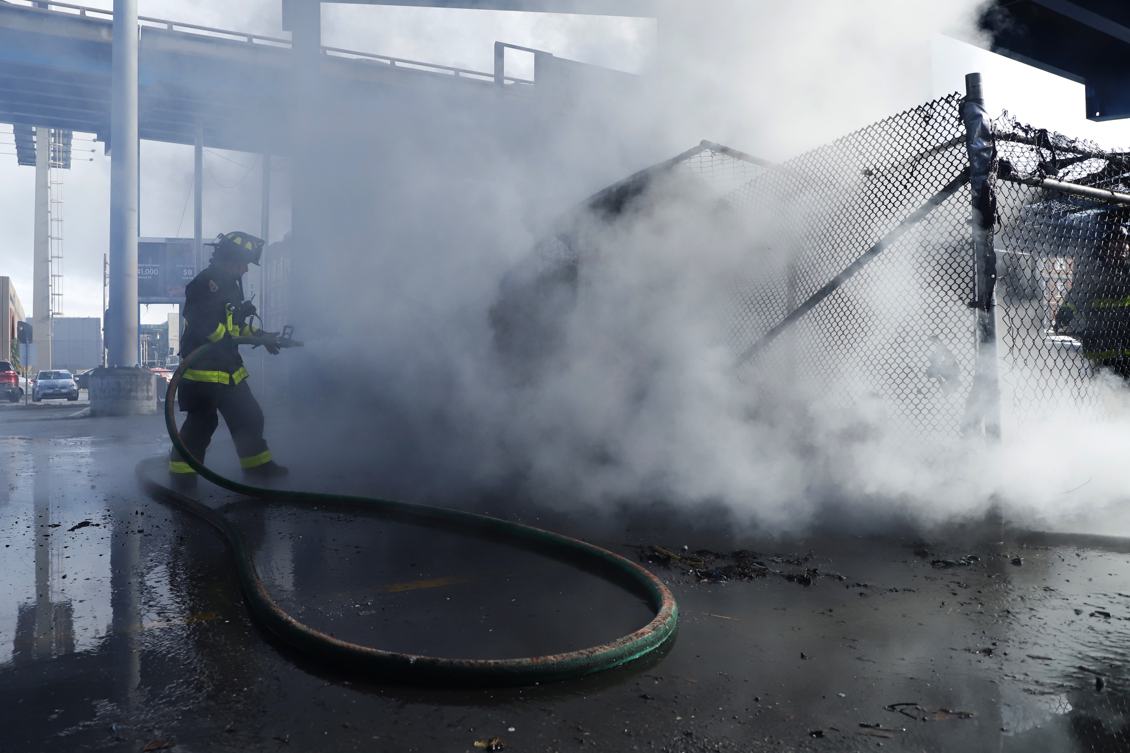 San Francisco Fire Department firefighters attempt to put out a homeless encampment fire in a CalTrans parking lot on Division Street.