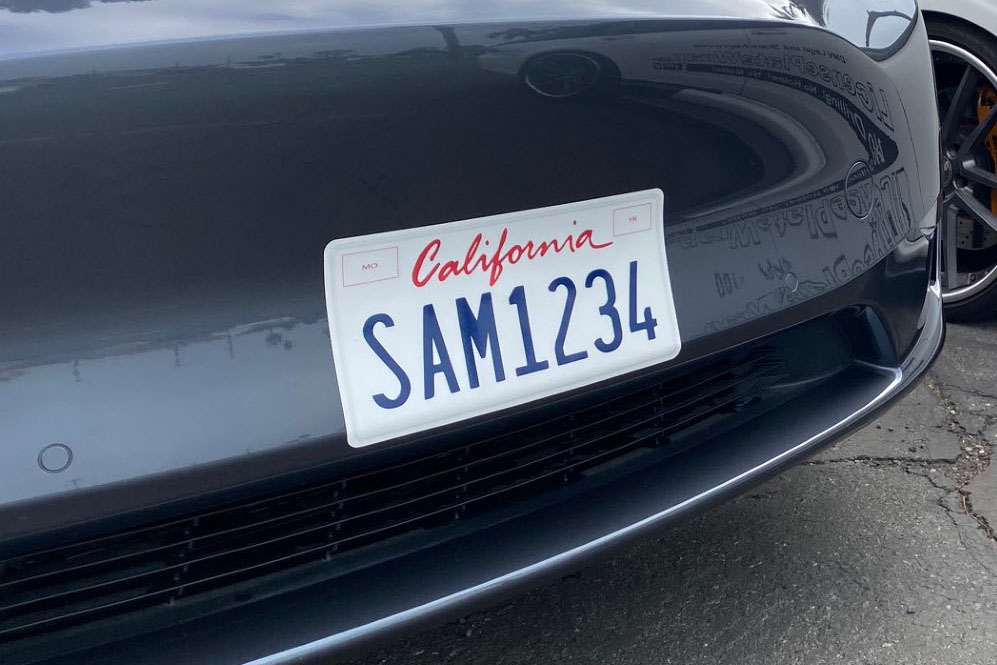 A wrapped sticker license plate adhered to front bumper on a vehicle with a California license plate.