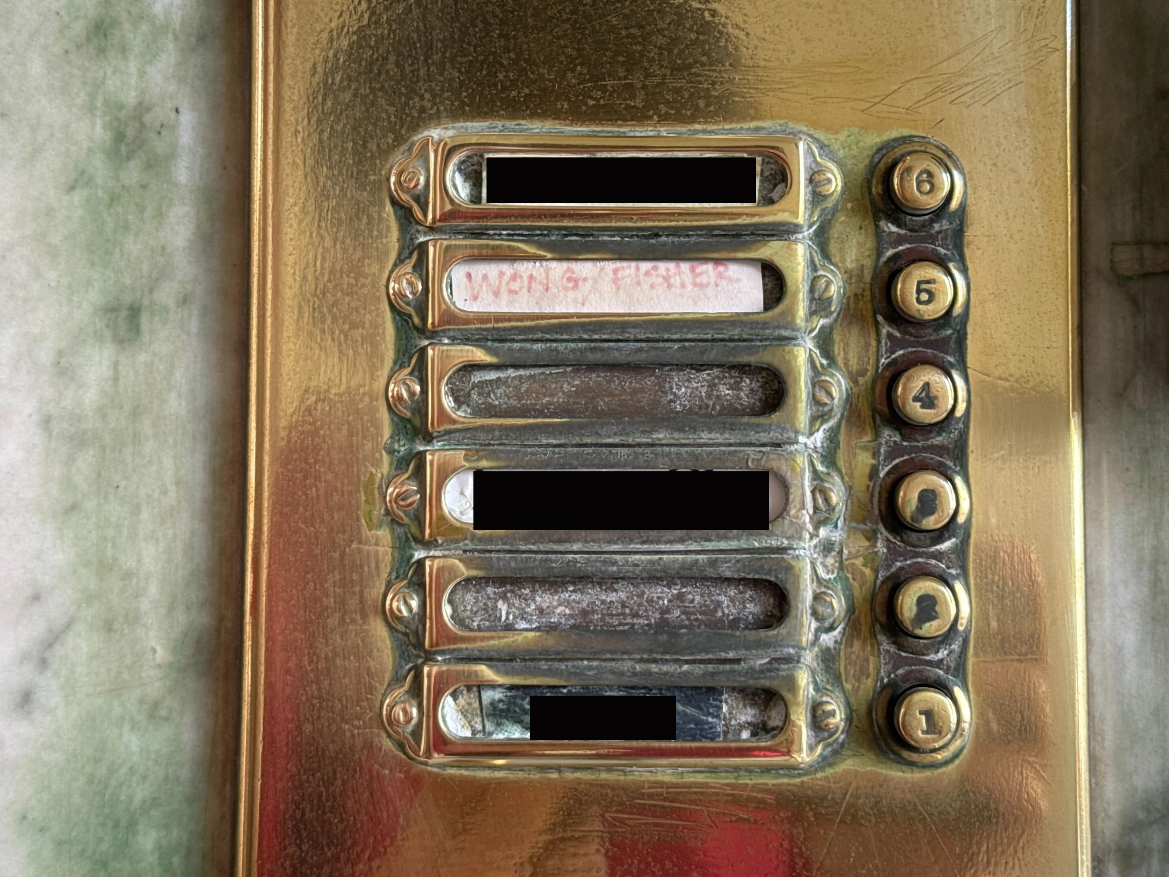 an apartment buzzer shows five buttons with names next to them