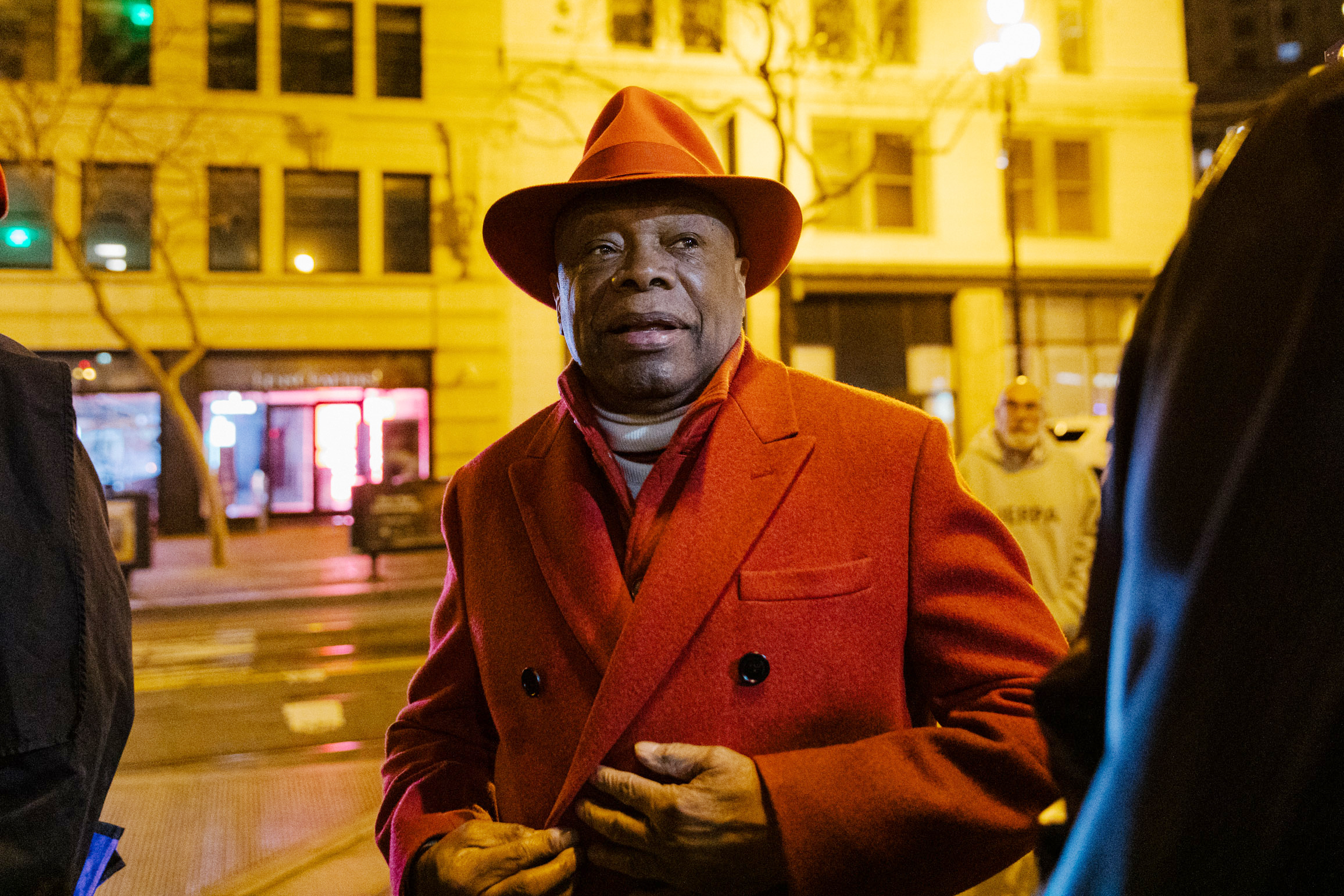 Willie Brown in a red suit and hat.