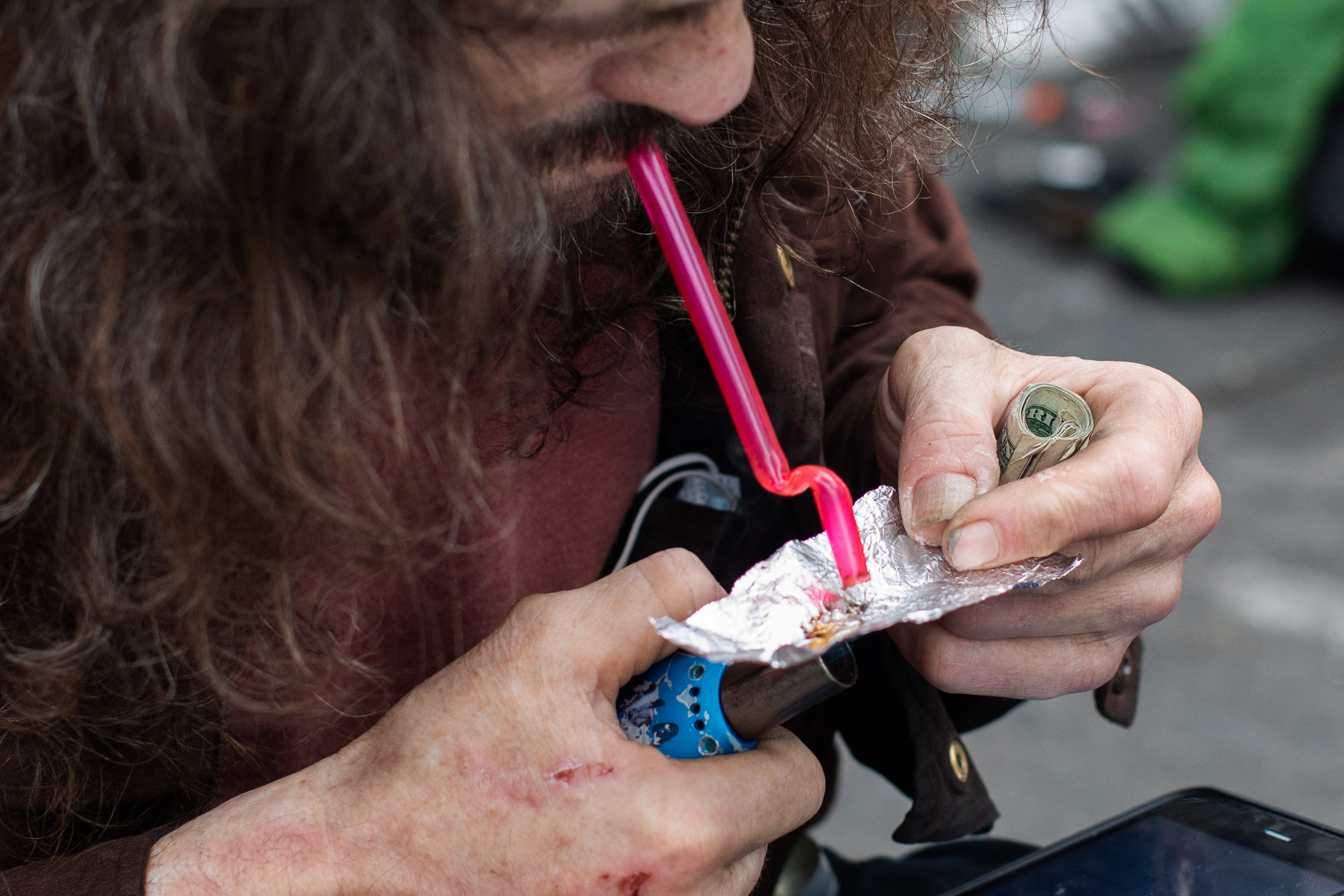 A man smokes drugs on tinfoil using a straw.