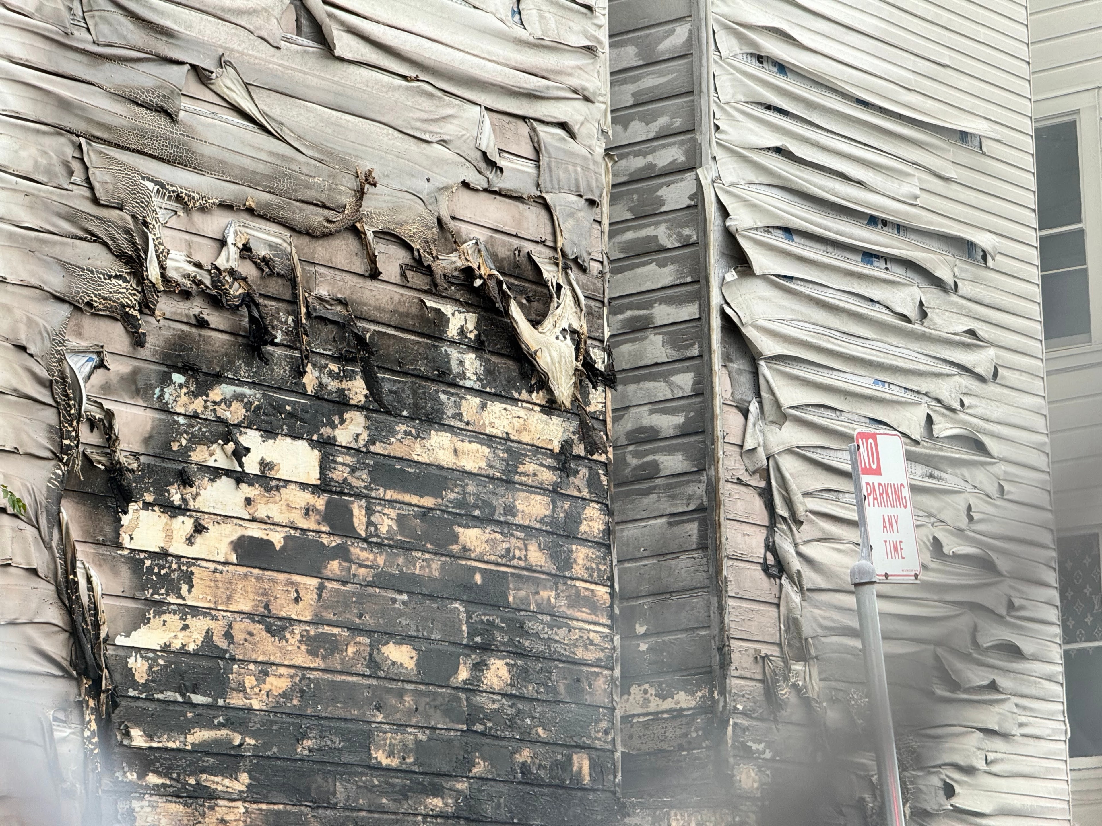 Damage to the side of a residential building after two cars were set on fire at a parking lot off Boardman Place on Jan. 2, 2024.