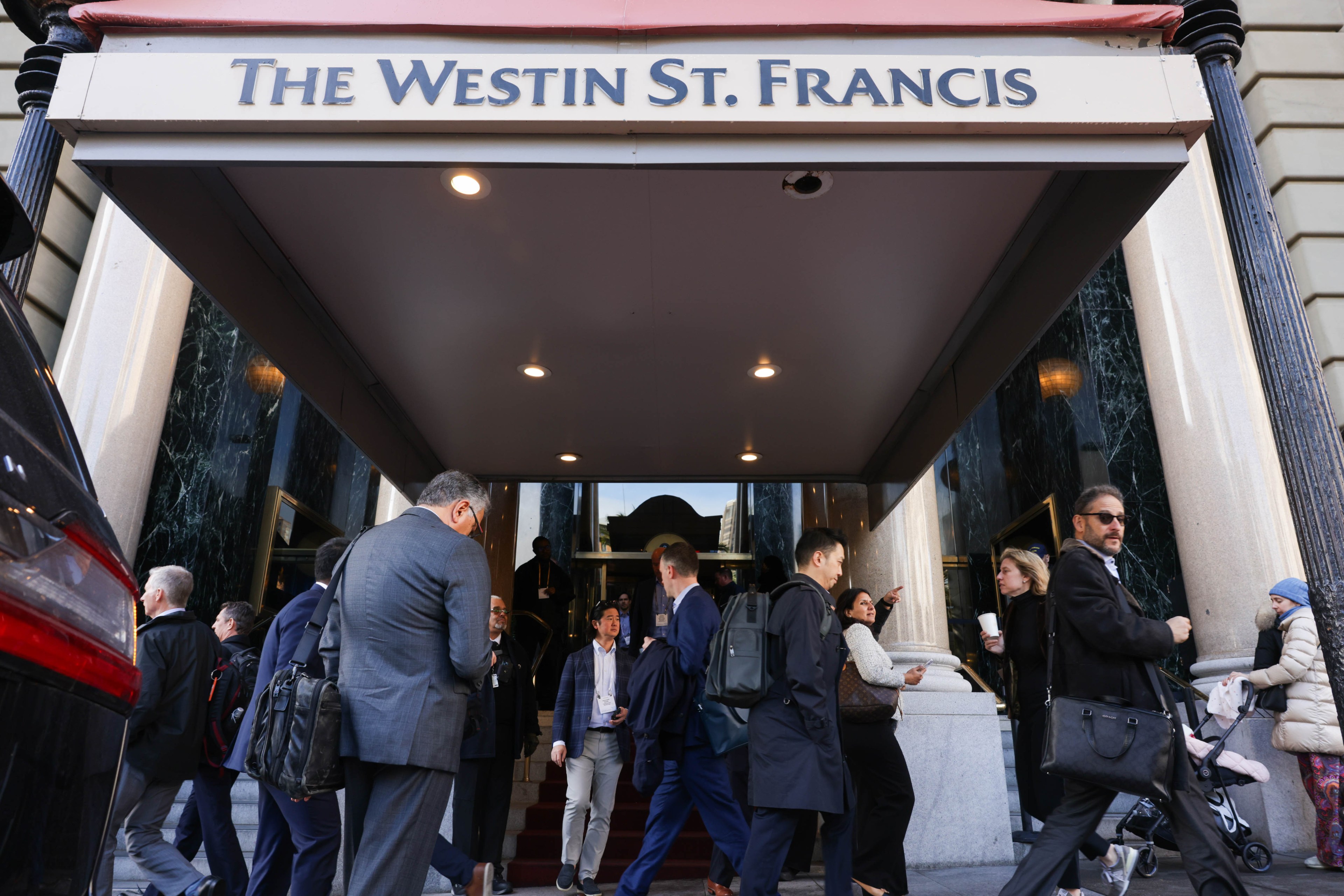 People walking in and out of the entrance of The Westin St. Francis hotel.
