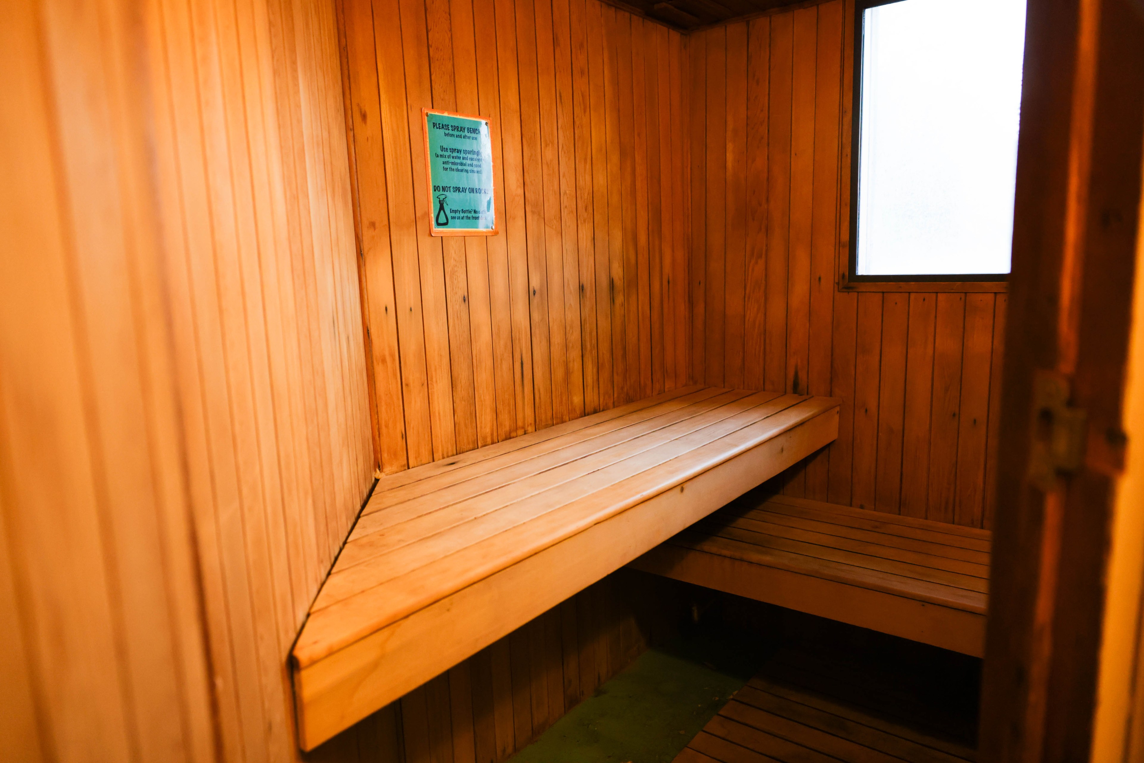 A wooden sauna interior with benches and a frosted window.