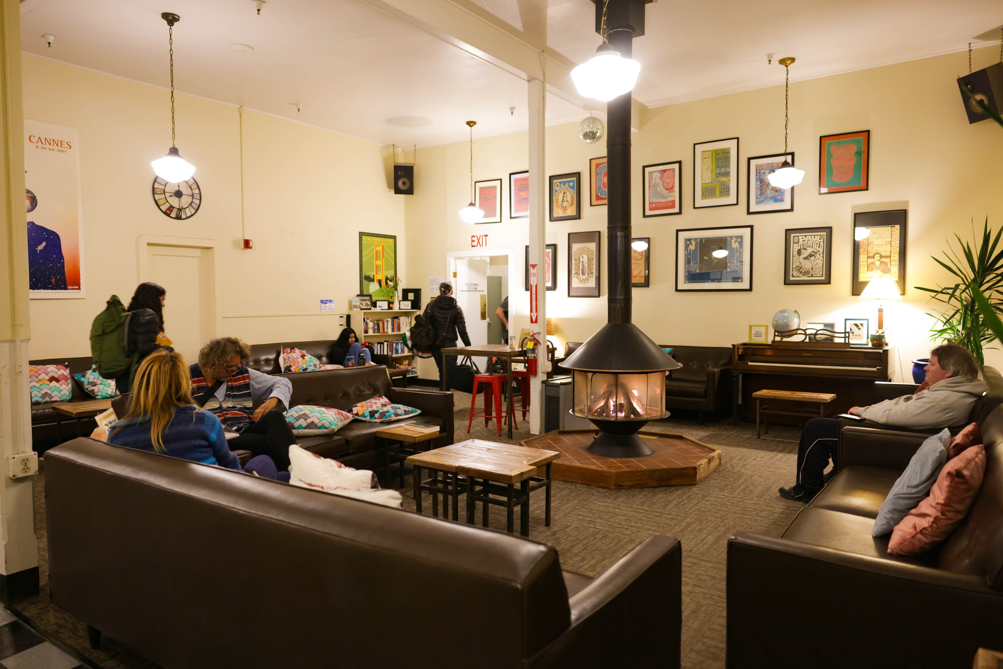 People around a fire place in the lobby of a hostel. 