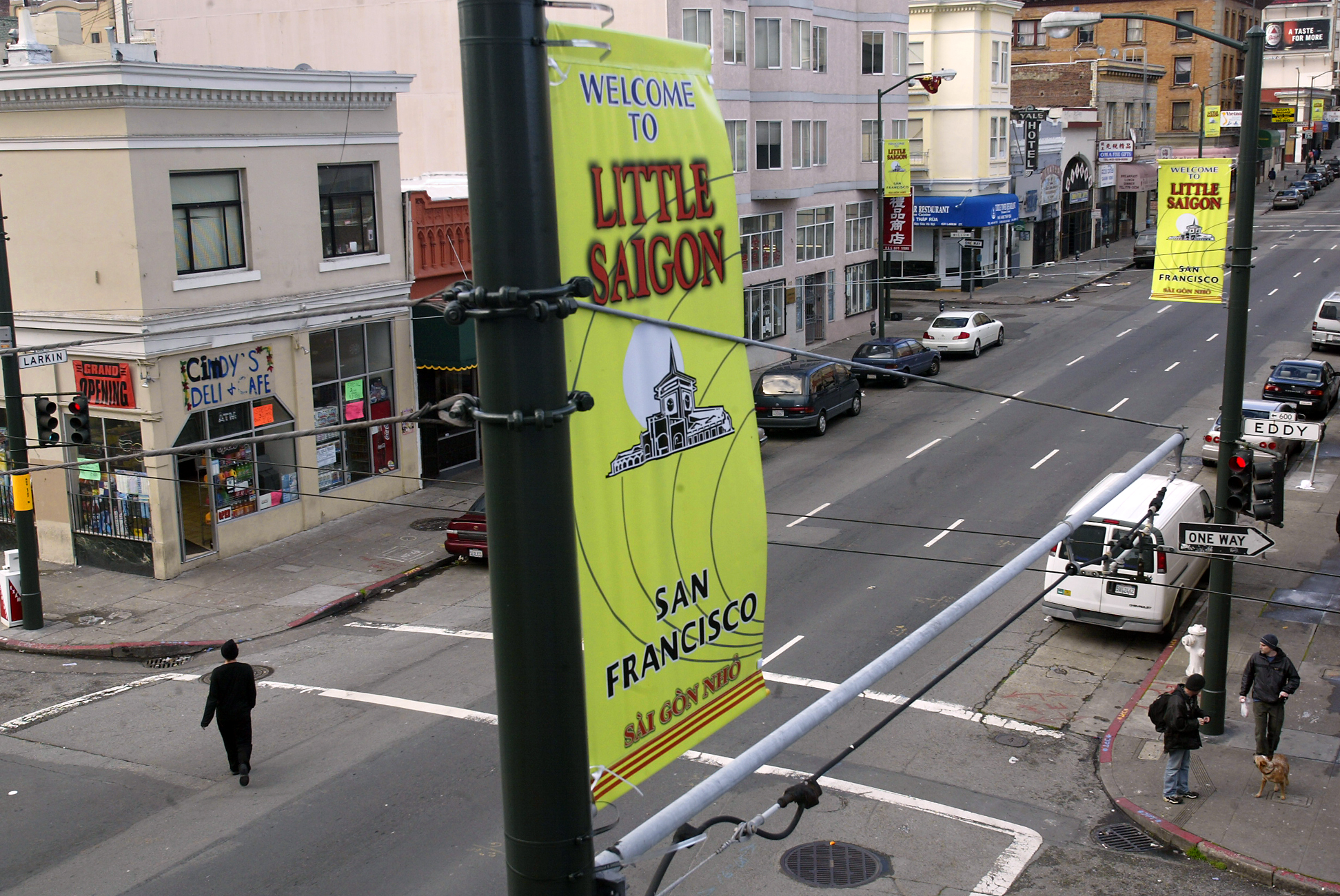 A street banner reads &quot;Welcome to Little Saigon, San Francisco,&quot; with people and cars on the urban street below.