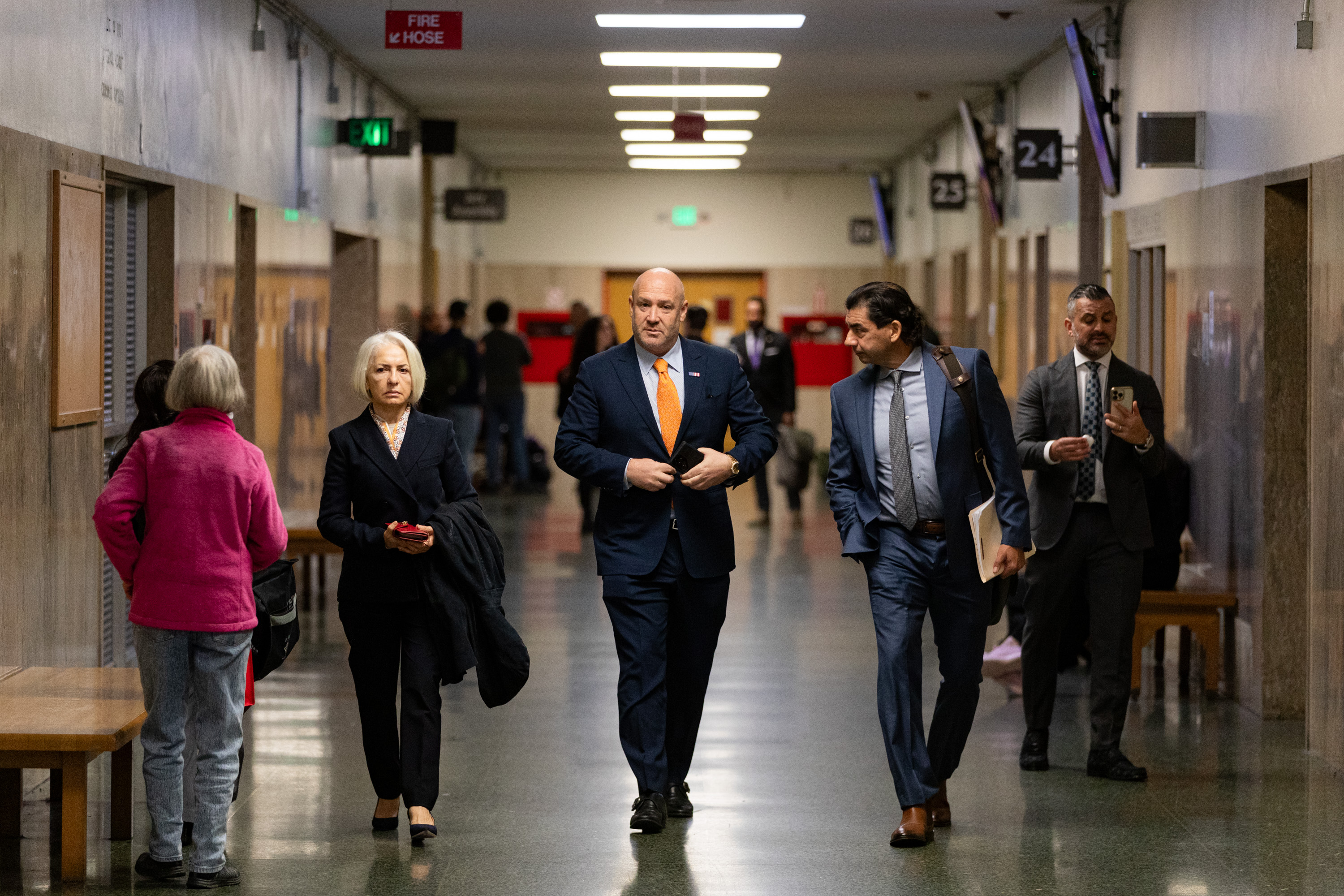 A group of people walk down a court house hallway. 