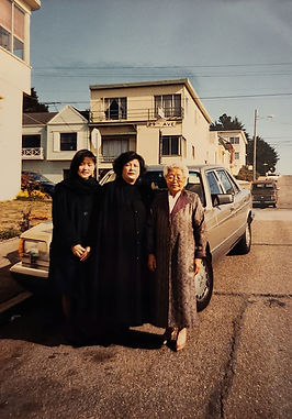 three woman stand in front of a car. 