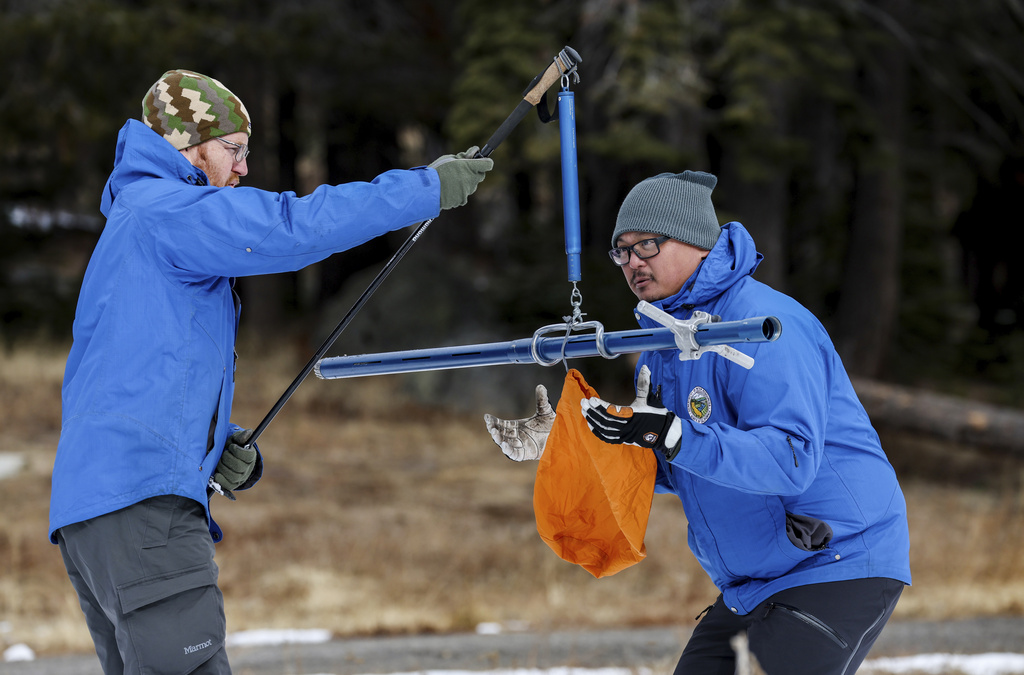 Two people in blue jackets use a weighing scale outdoors.