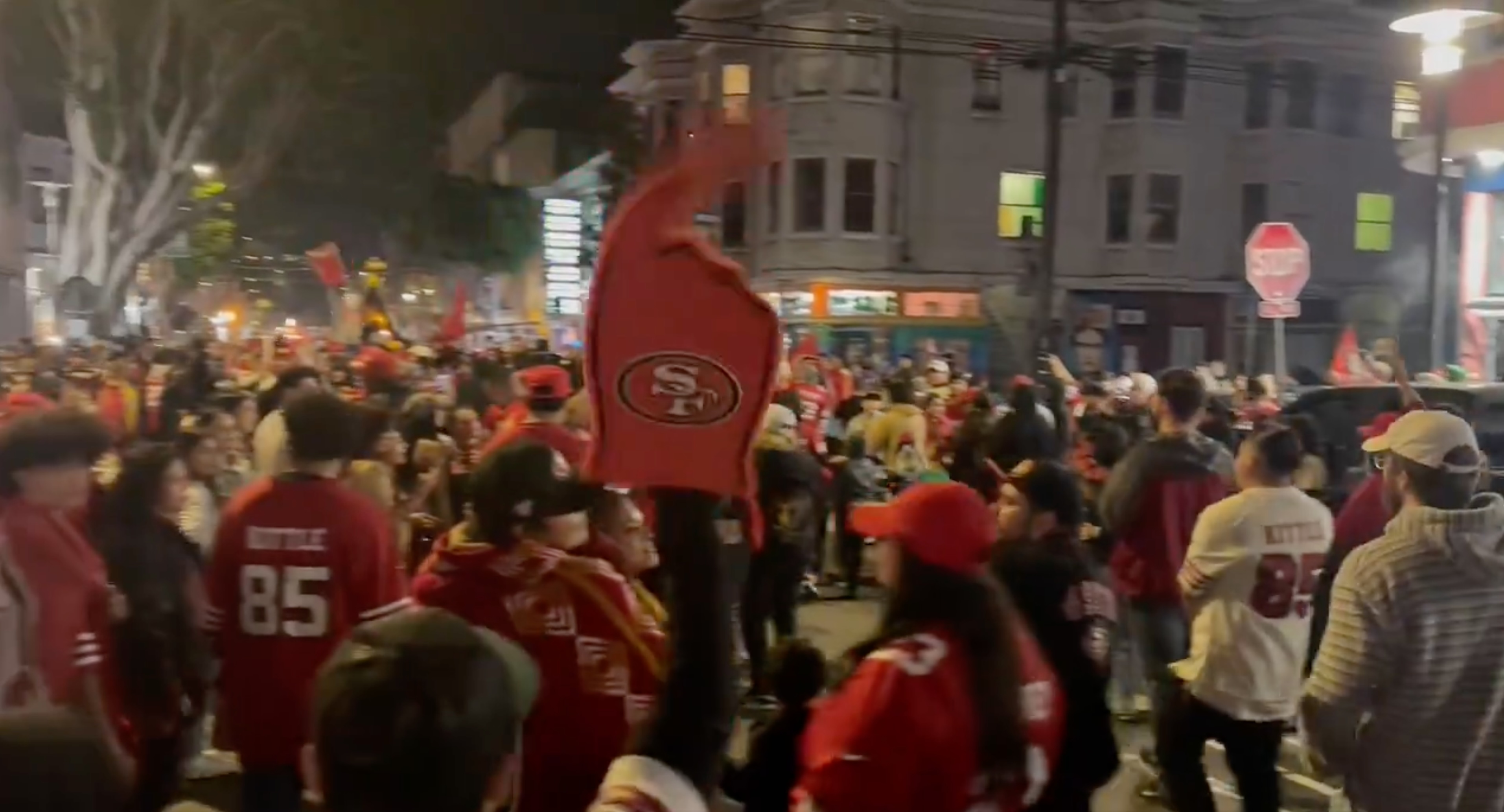 A crowd of red and gold clad sports fans celebrate in a city intersection.