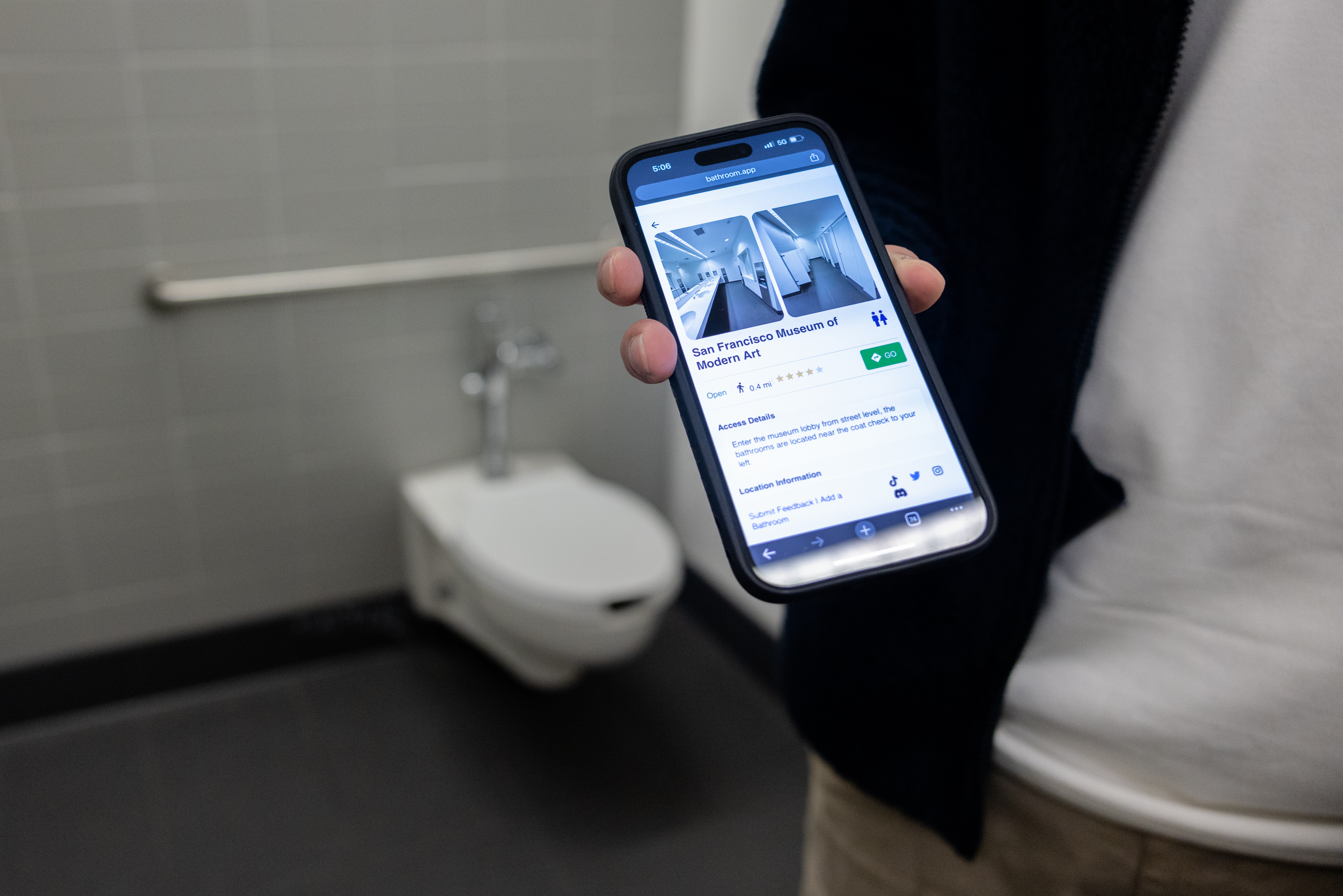A phone shows a web browser featuring photos of a bathroom