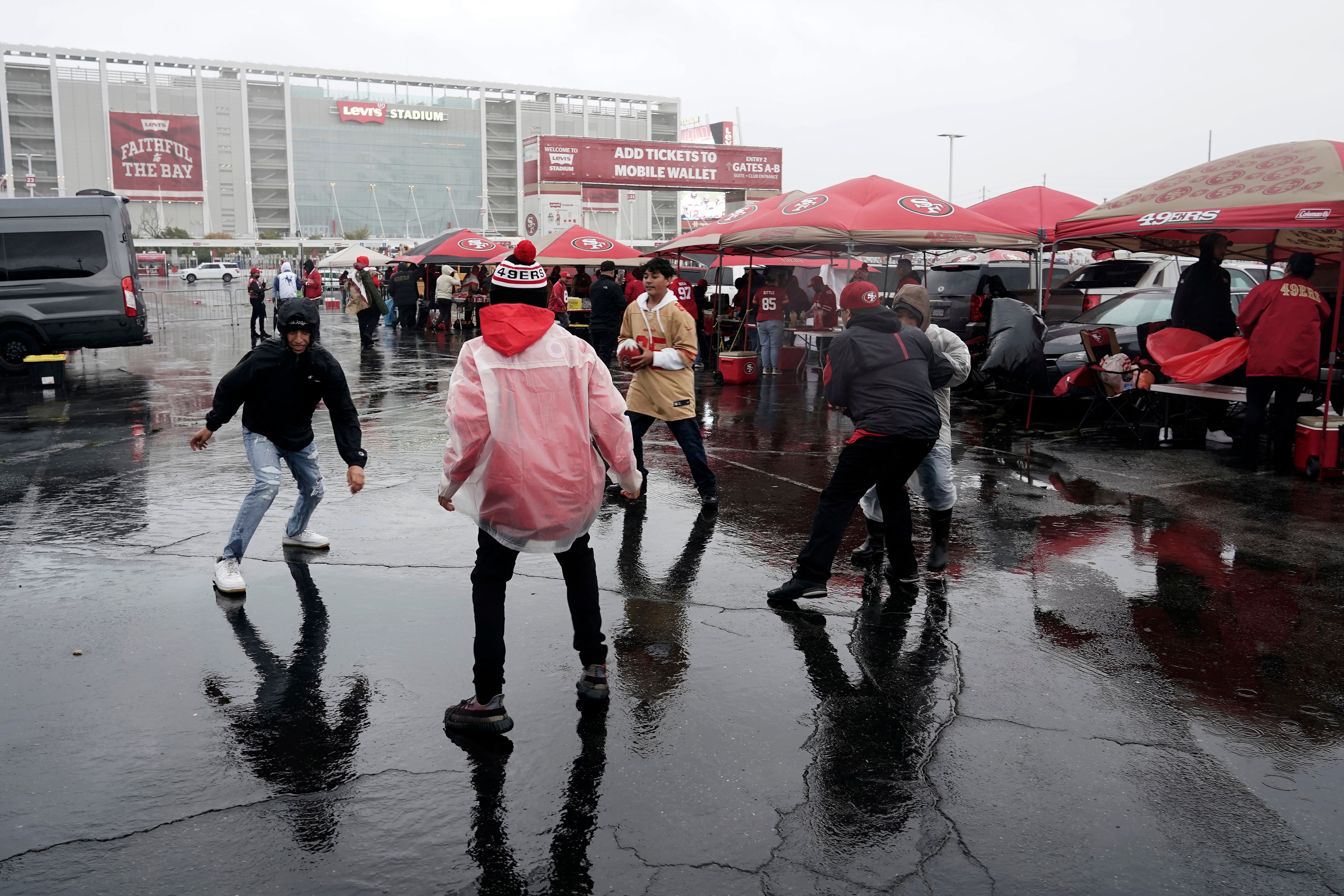 Fans walk in wet weather outside a staidum