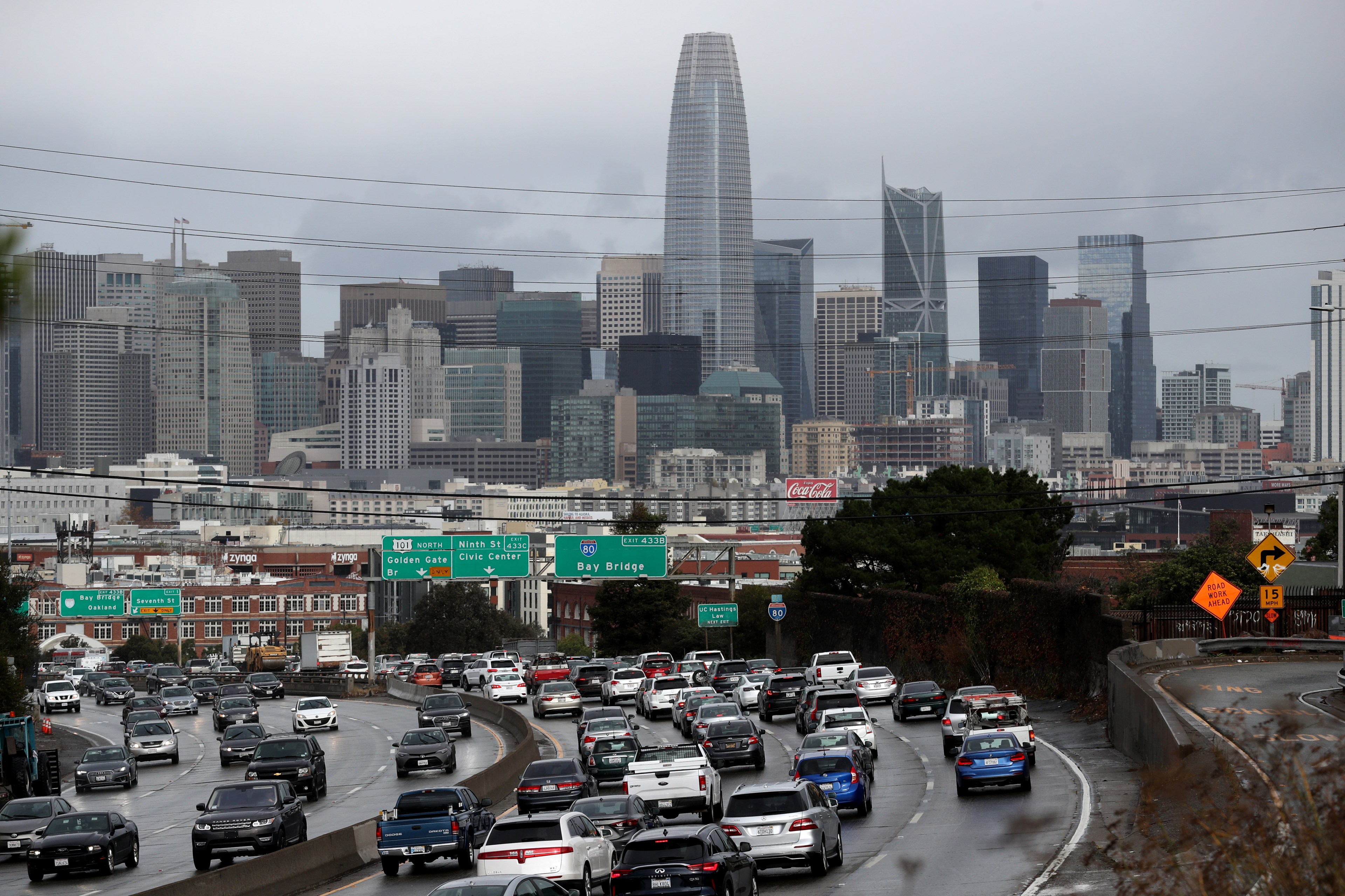 Traffic moves along a freeway with the San Francisco skyline in the background