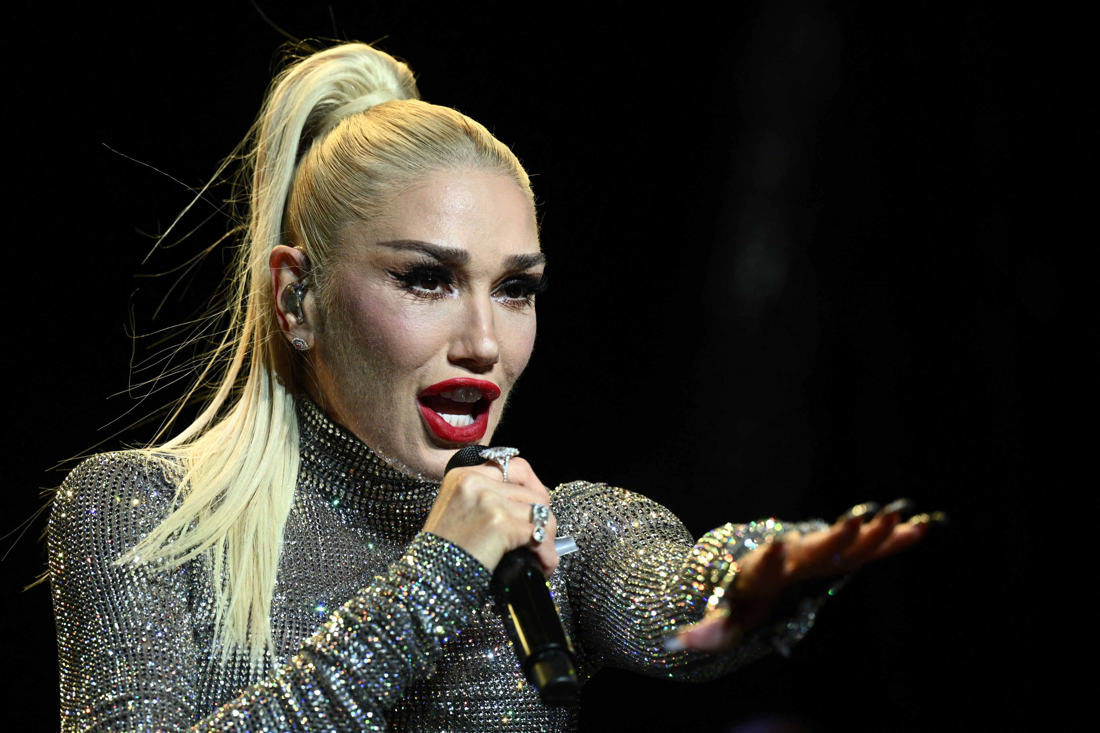 A close up of Gwen Stefani in a blond ponytail and sequin dress