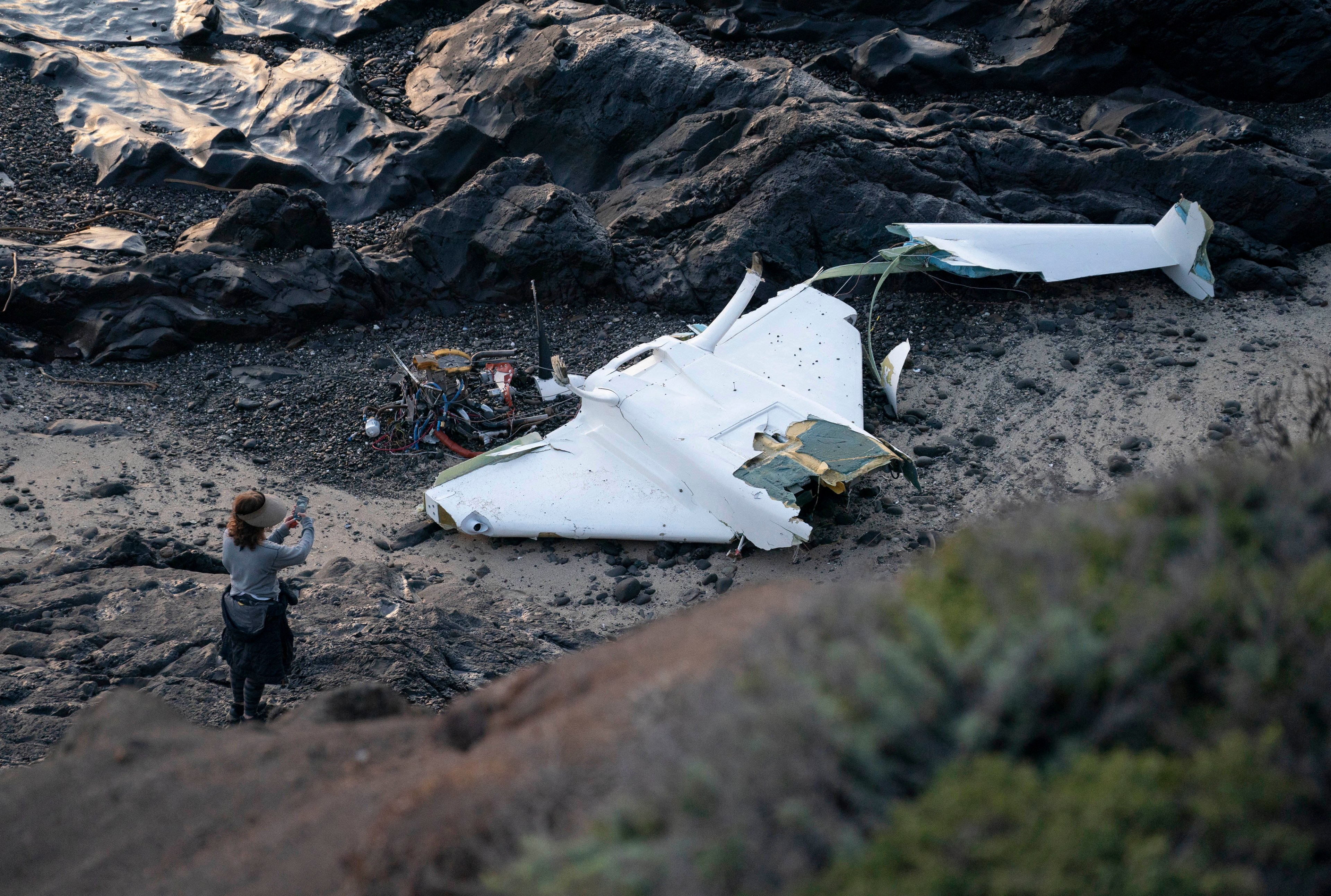 The shell of a wrecked plane lies on a beach.