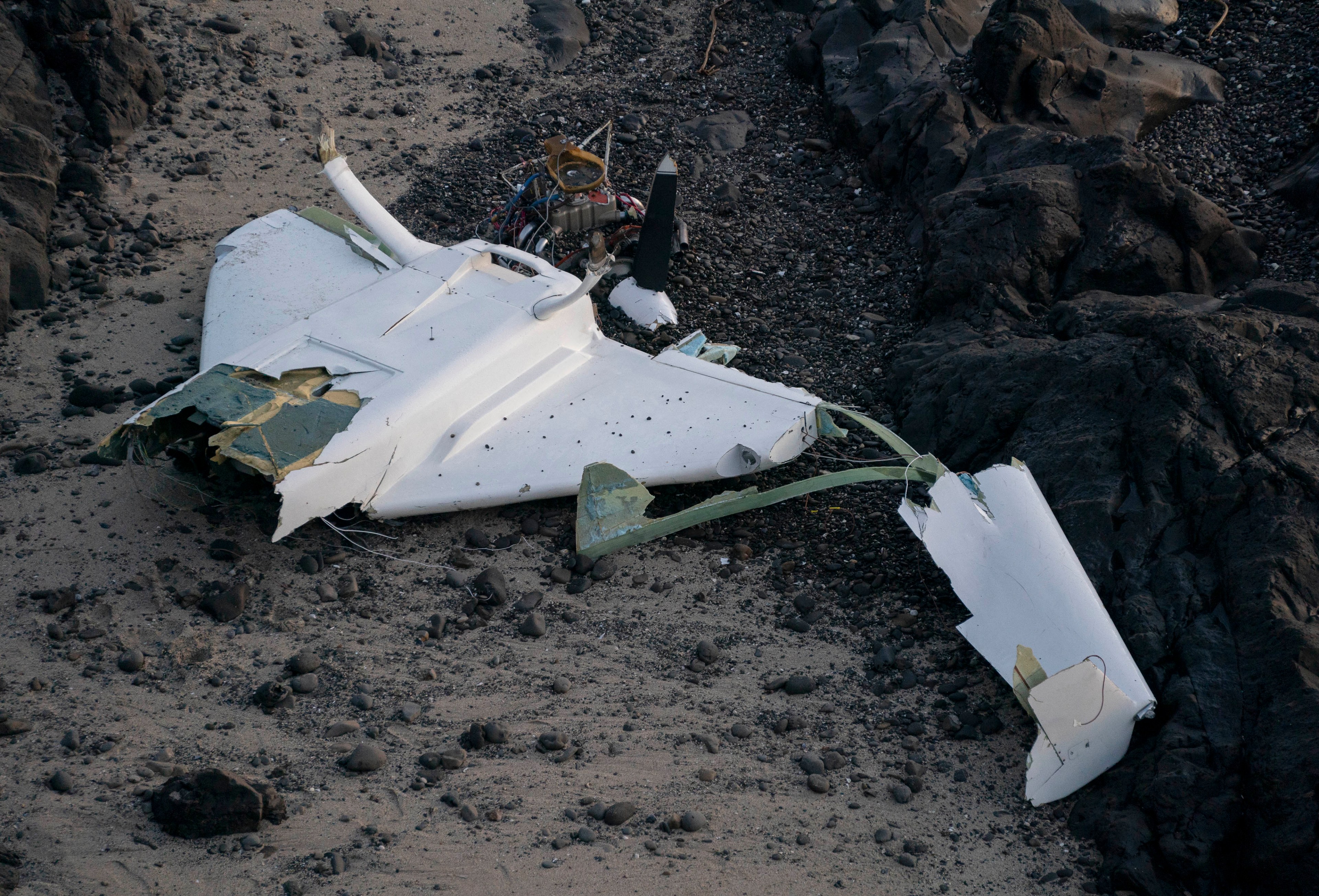 the shell of a broken plane lies on a beach