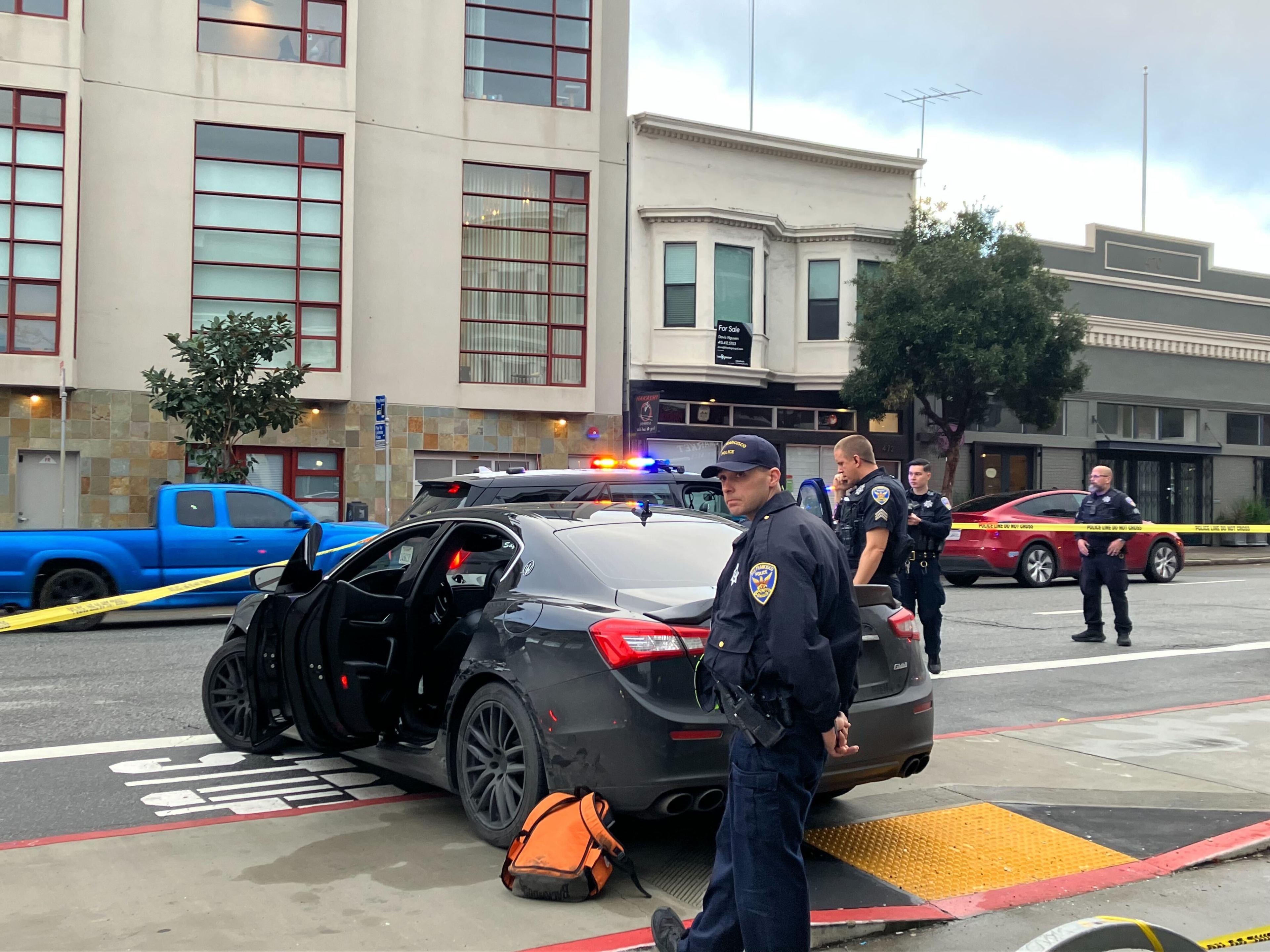 San Francisco police stand near a Maserati that collided with a Muni bus during a police pursuit on Wednesday, Jan. 24, 2024.