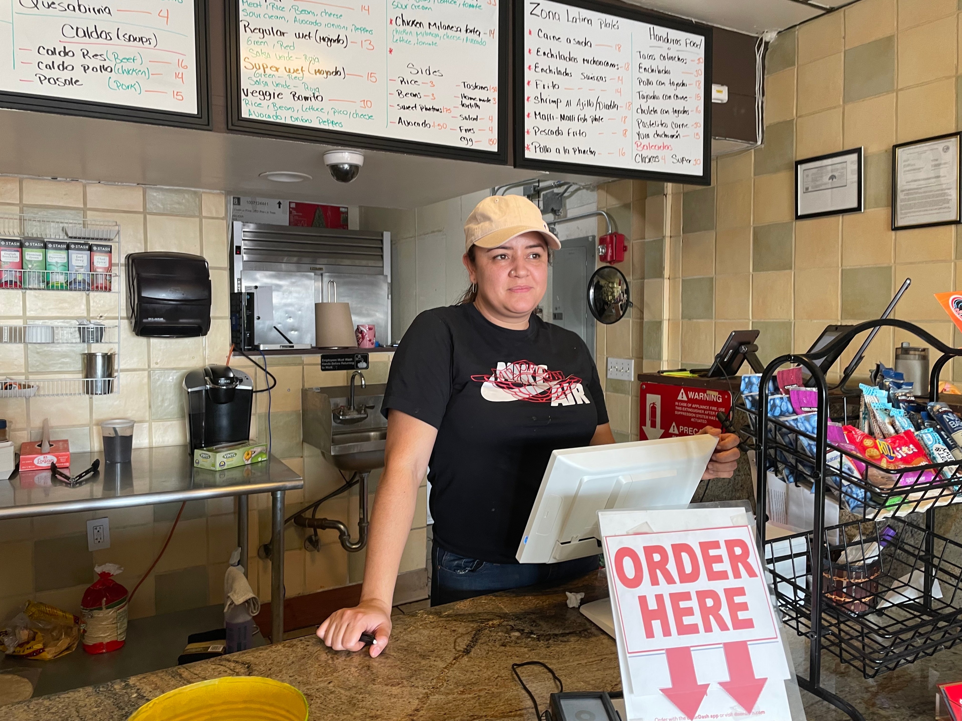 A woman stands behind the cash register at a taqueria.