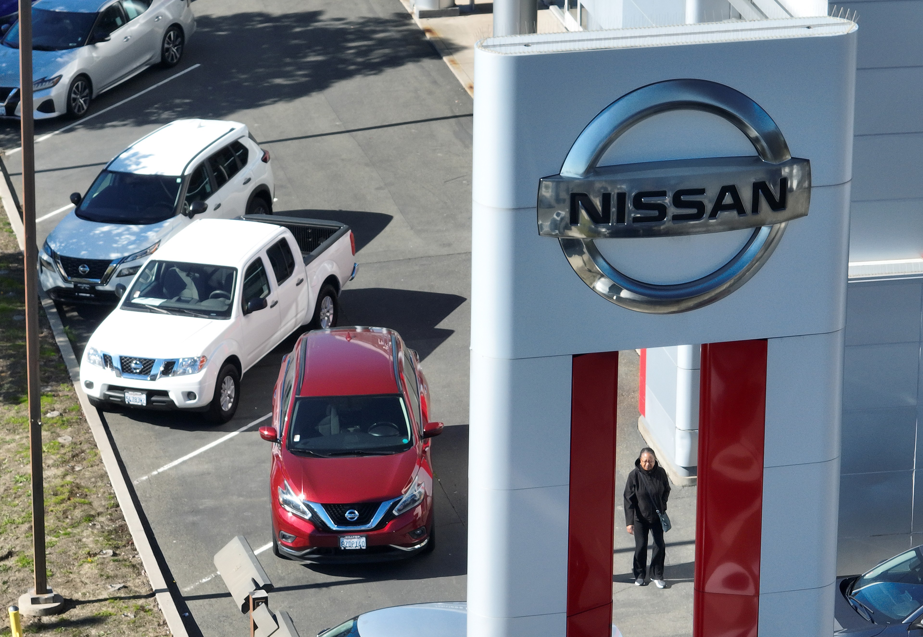 An aerial view of a Nissan dealer, including a customer and several cars.
