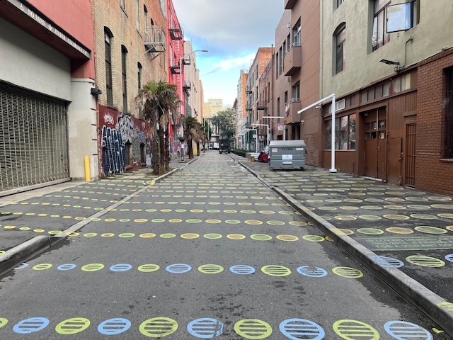 An small alleyway has blue and green dots on it. 