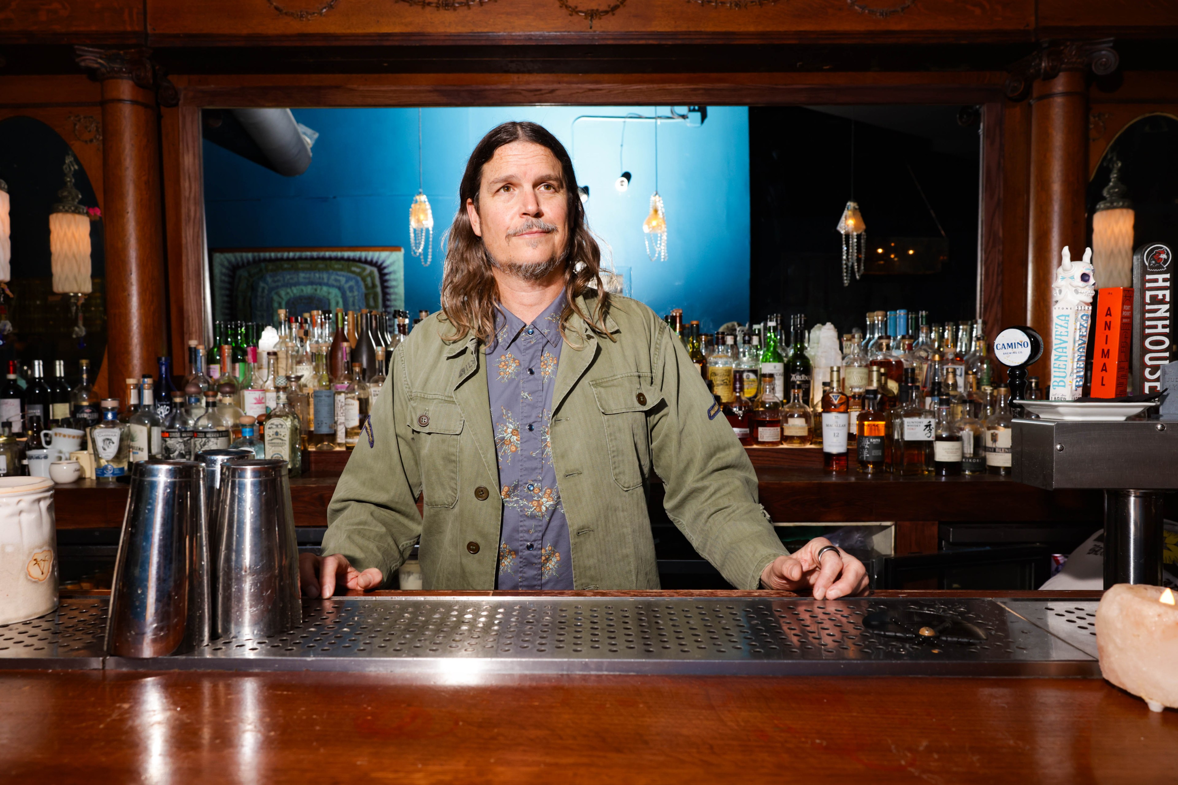 a white male bartender stands behind a bar