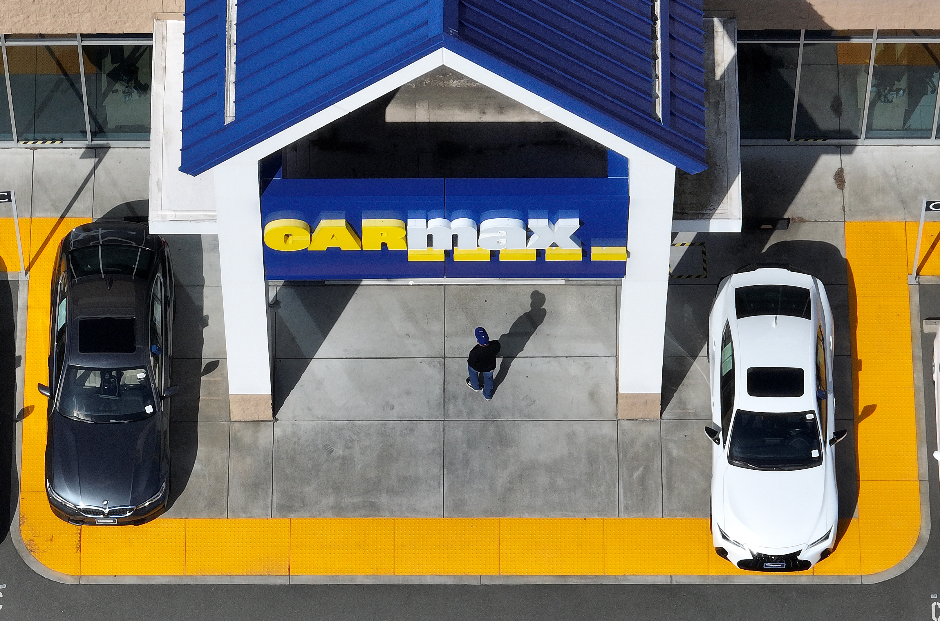An aerial view of a person entering a Car max dealership.
