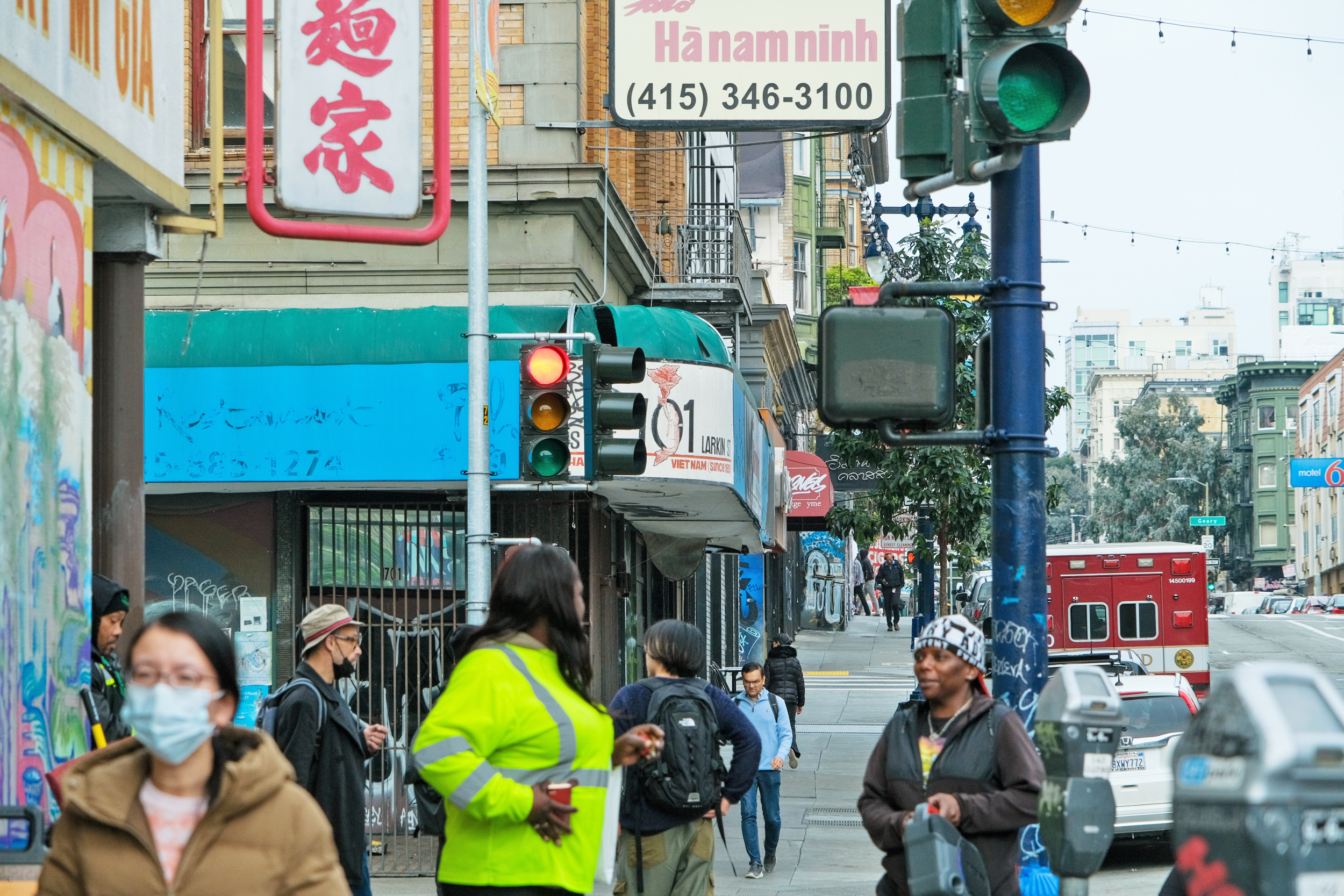 City street scene with pedestrians, traffic lights, Asian signage, and a Larkin Street sign.